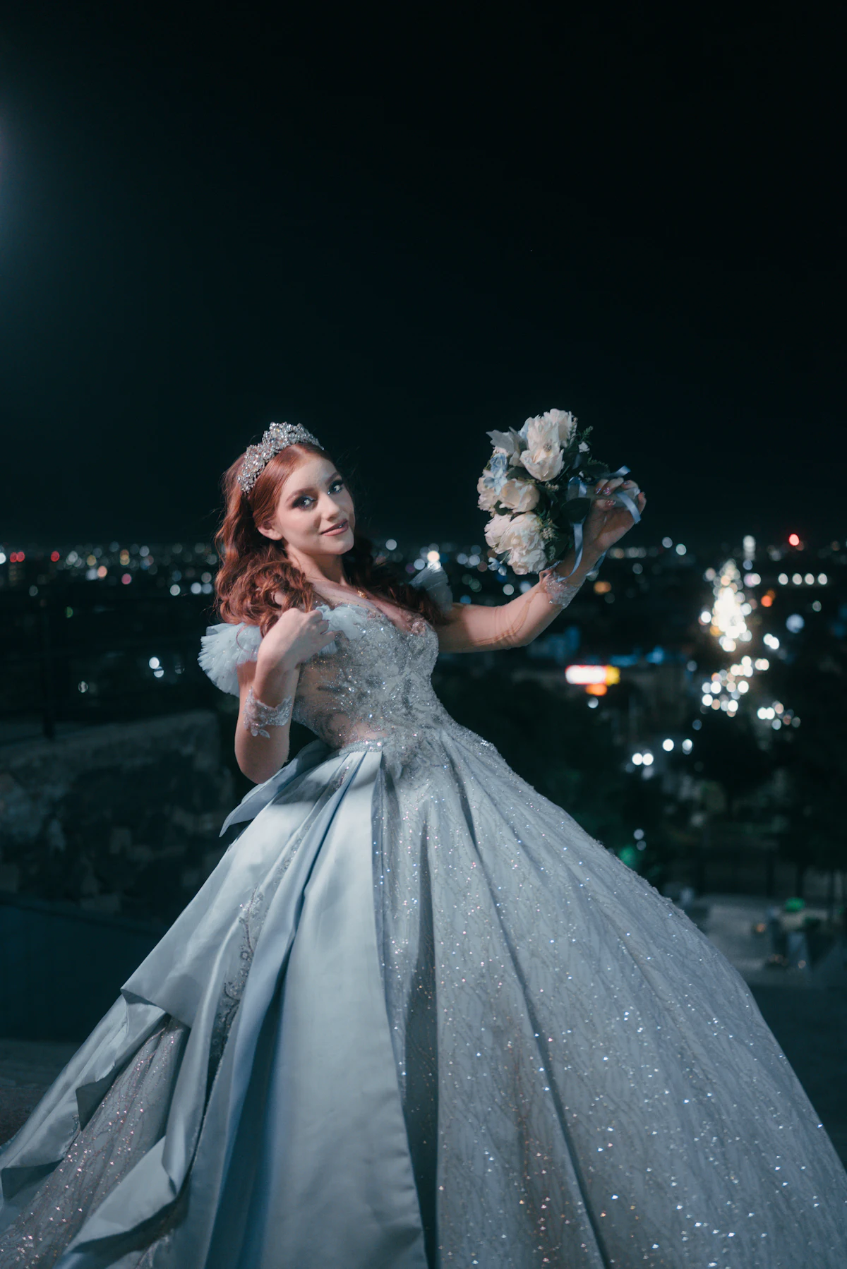 Quinceañera con vestido de gala celeste y un ramo, de noche