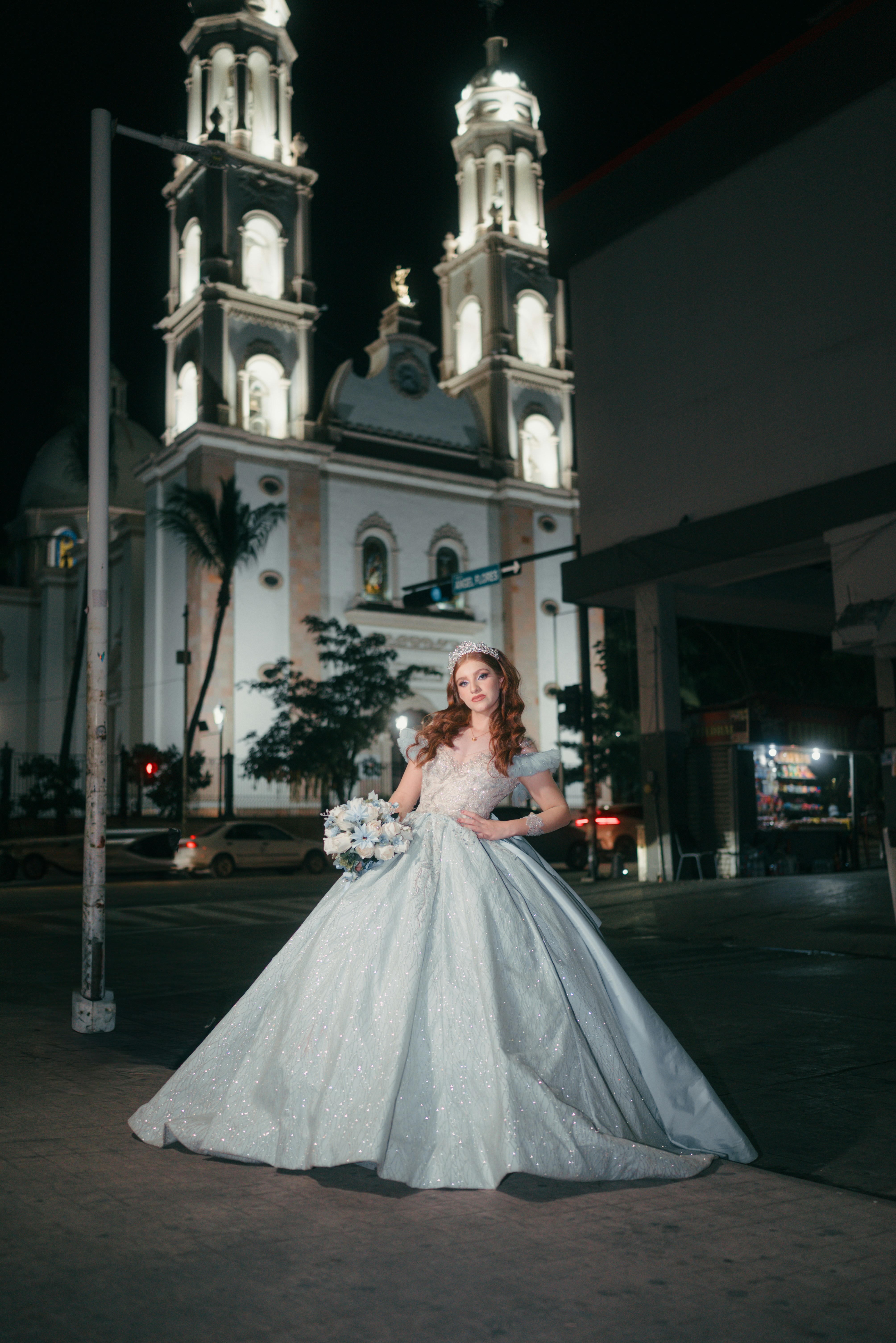 Bride in a sparkling dress outside church at night.