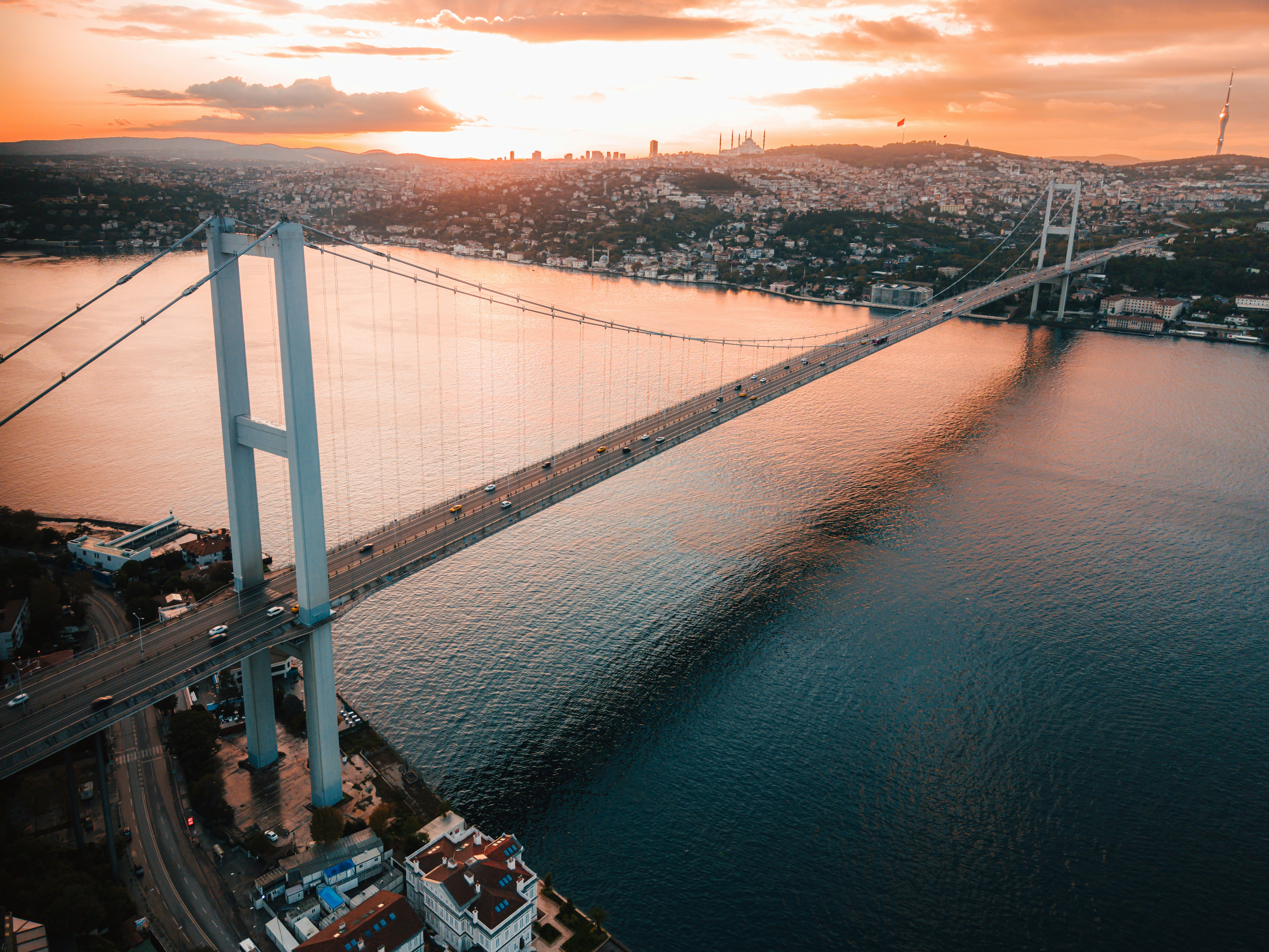 Suspension bridge over a wide river at sunset.