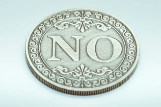 A decorative coin with the word no