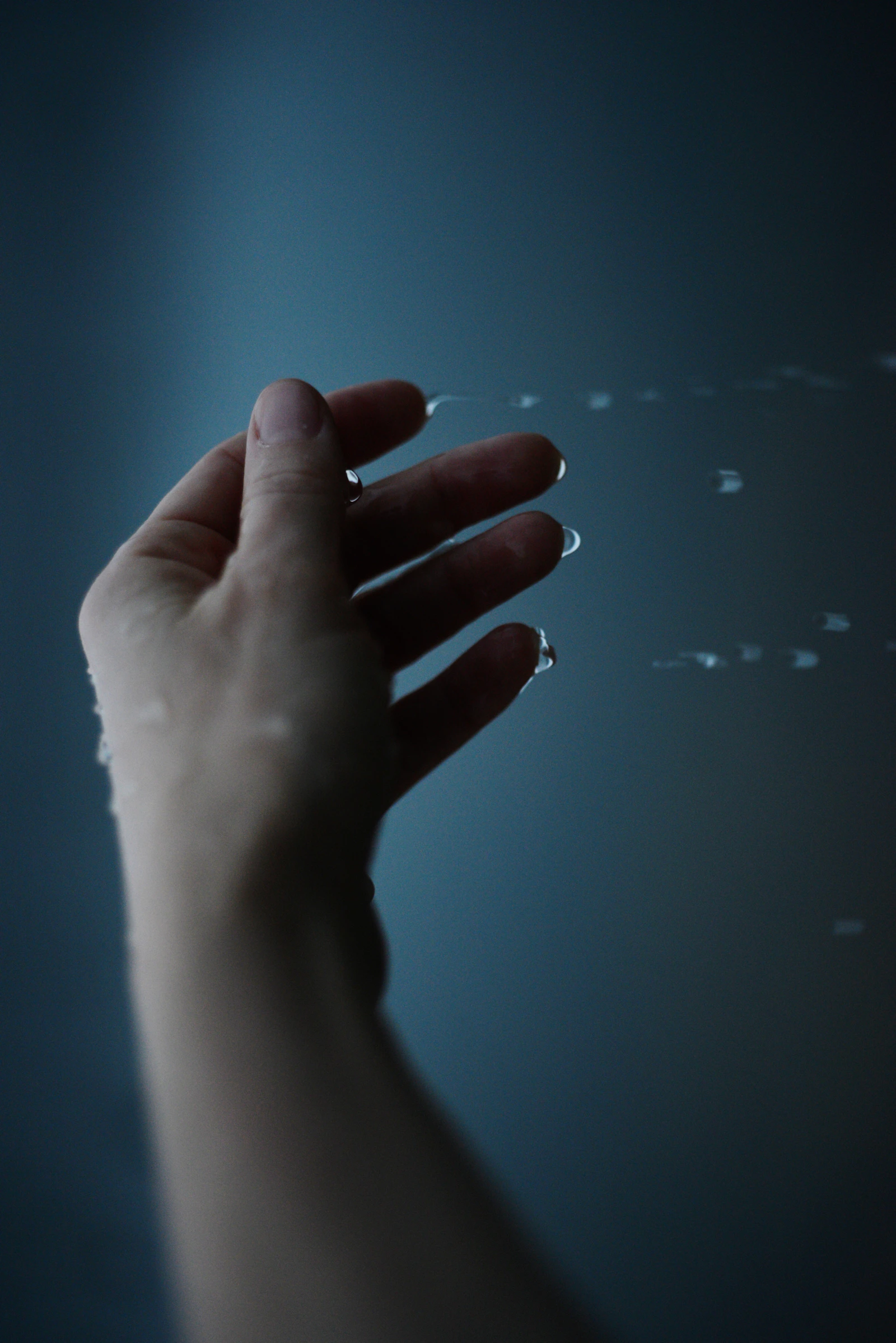 Hand moving gently through water droplets