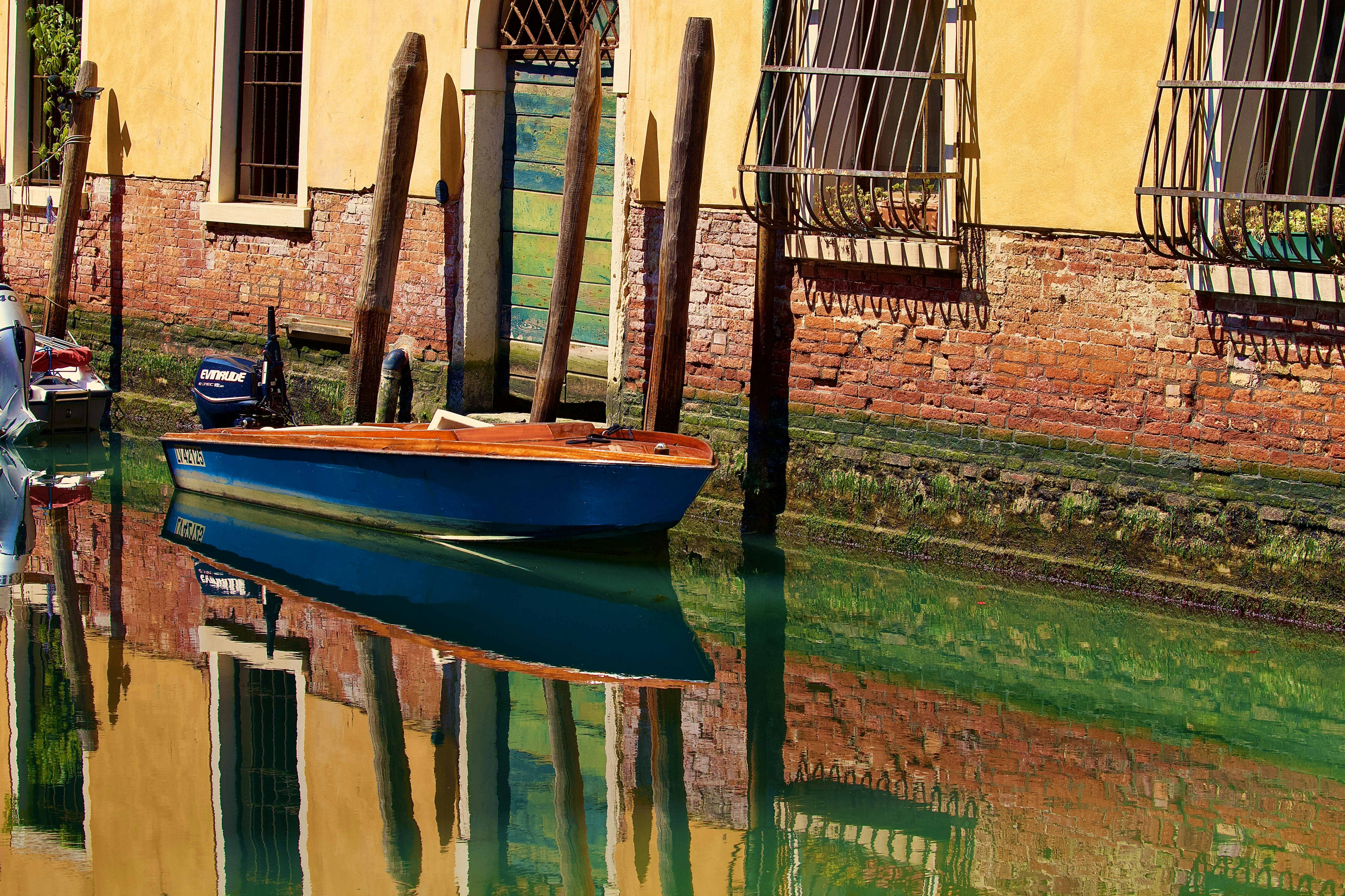A small blue boat floats on a canal in venice.