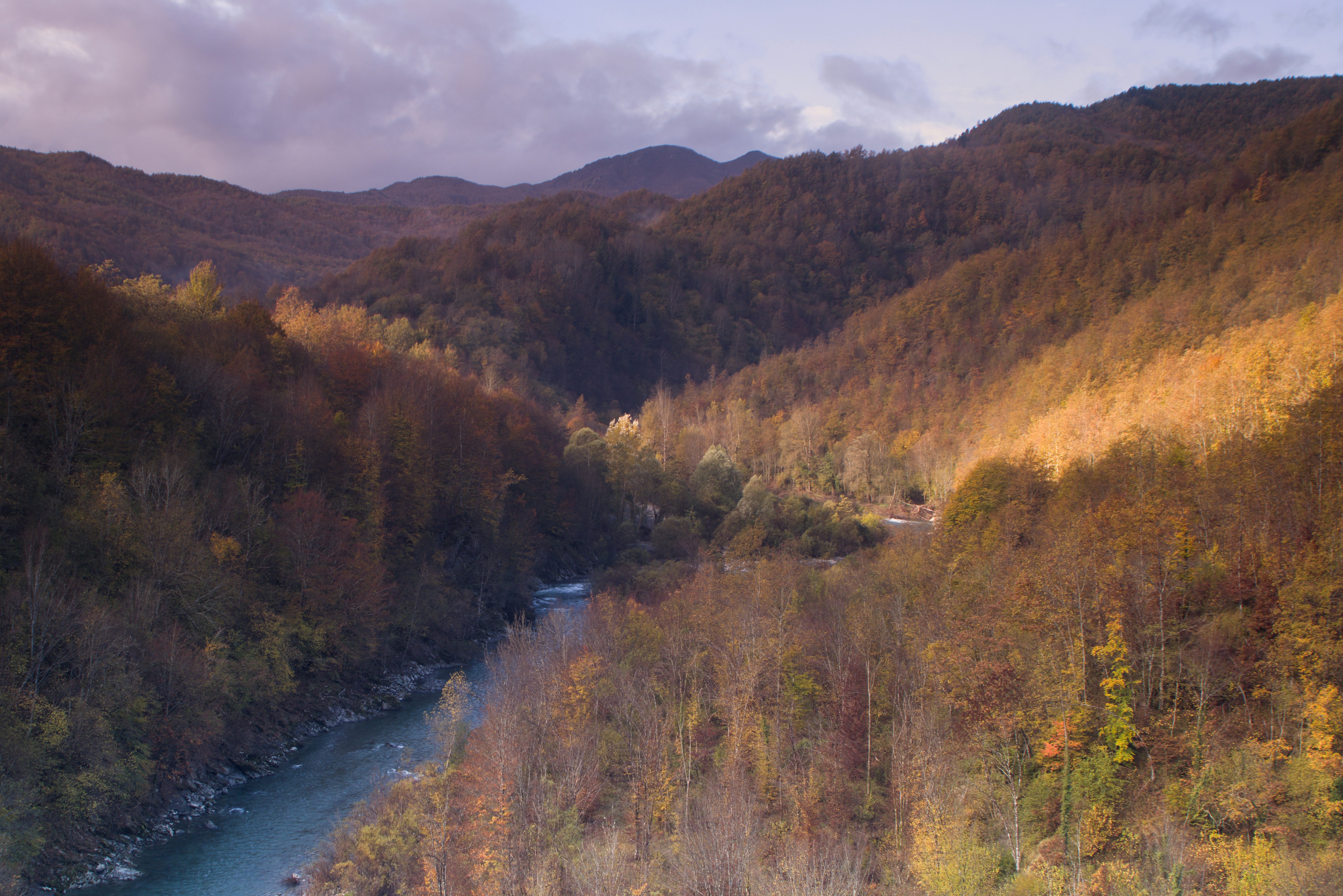 Valle montuosa con un fiume in autunno.