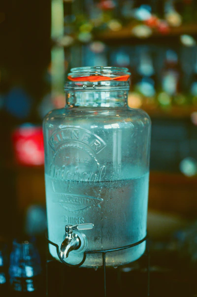 Glass beverage dispenser with tap filled with water