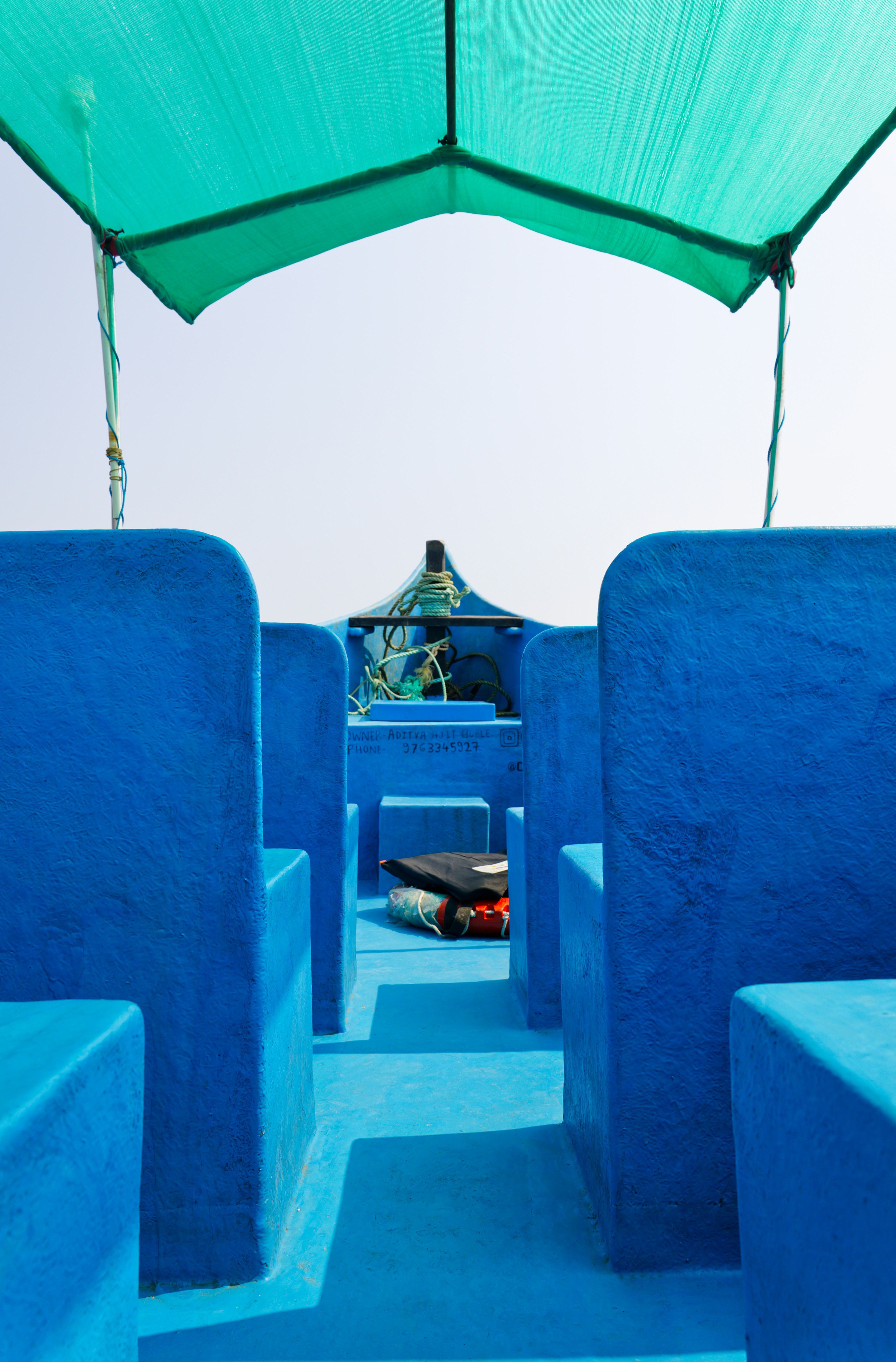 Blue seats under a green canopy on a boat