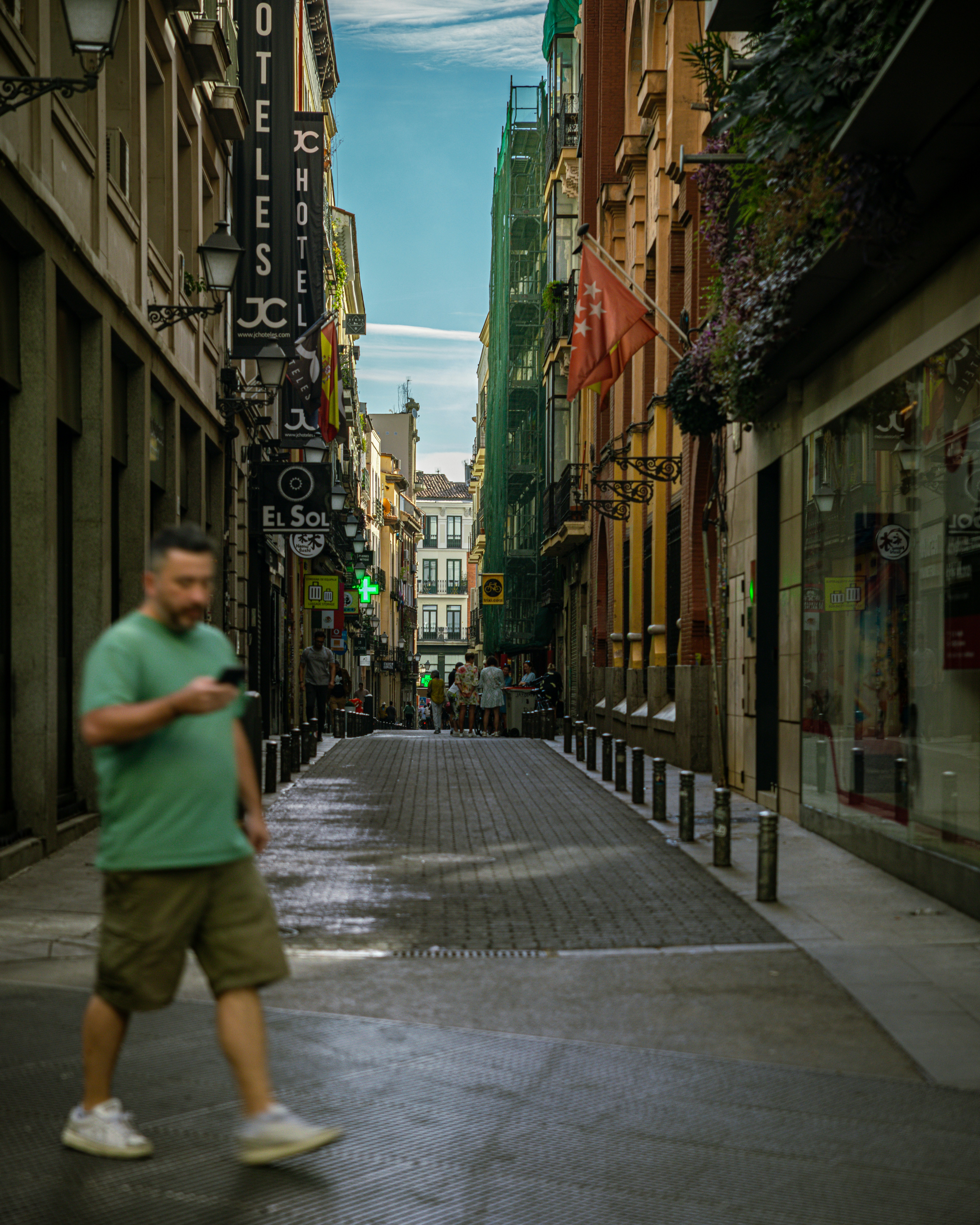 Man walks down a narrow street in a city.