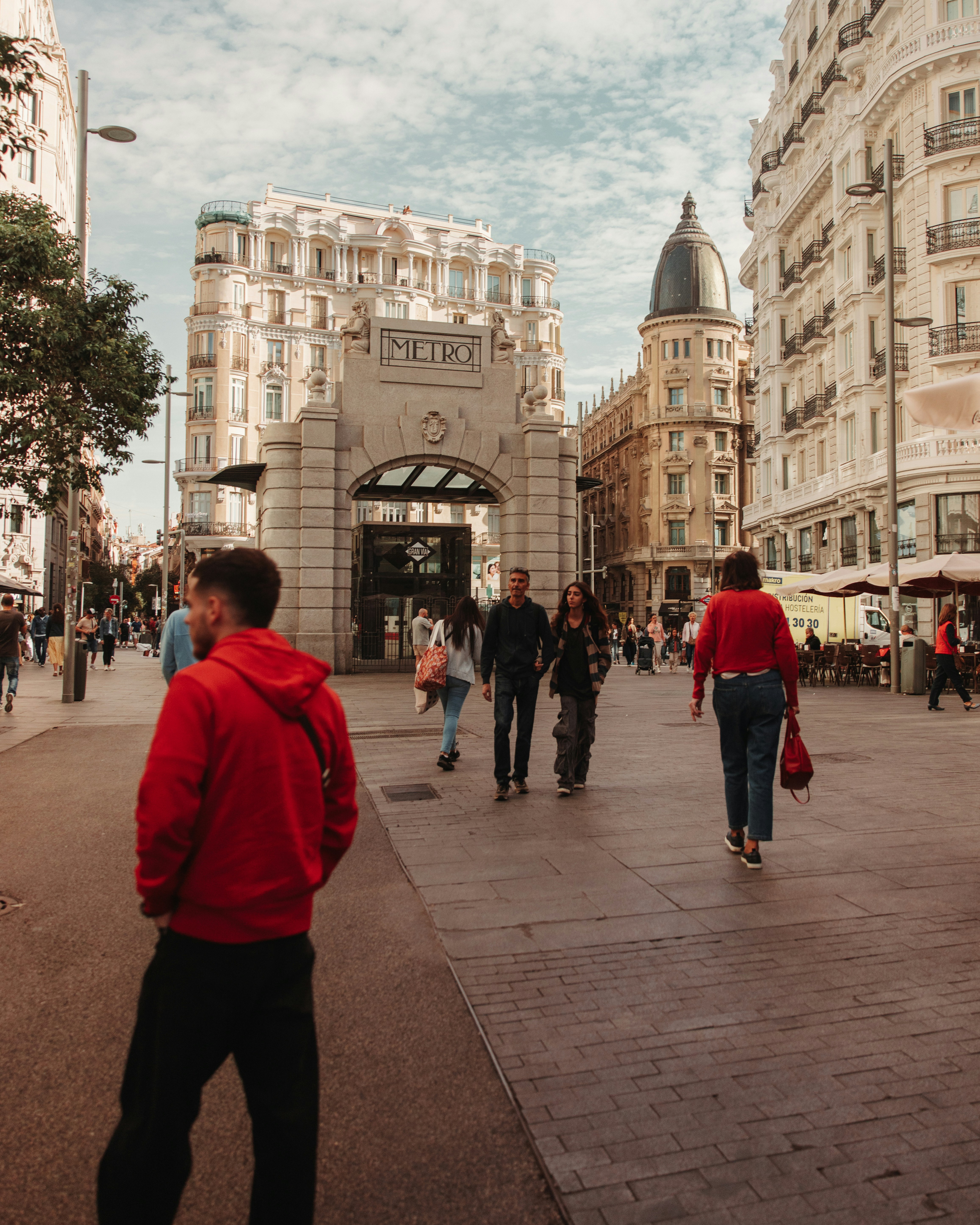 People walking on a city street near metro entrance.