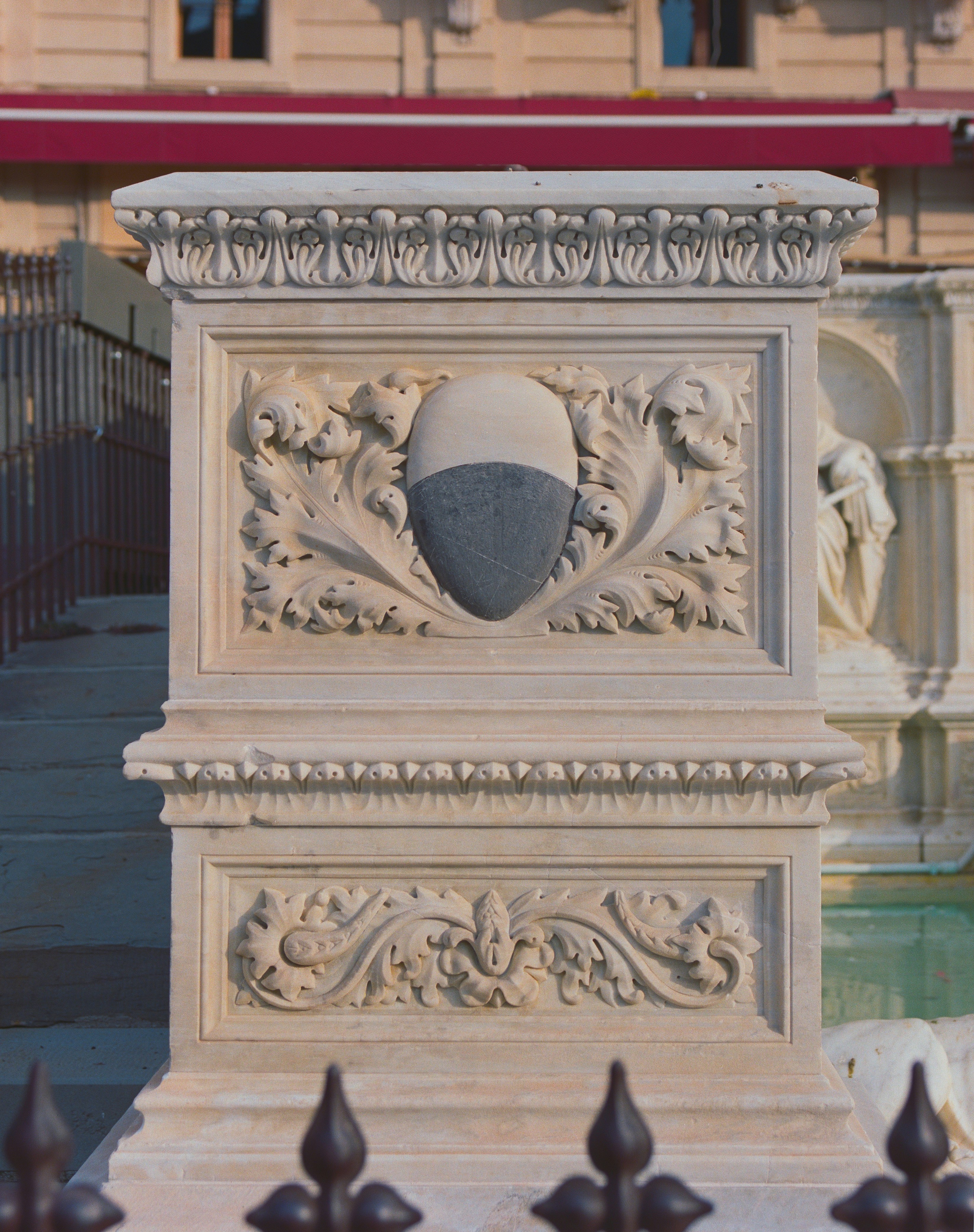 Ornate stone pedestal with carved shield and foliage