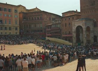 Crowd gathered in a large, historic italian piazza.