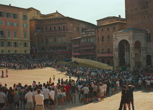 Crowd gathered in a large, historic italian piazza.