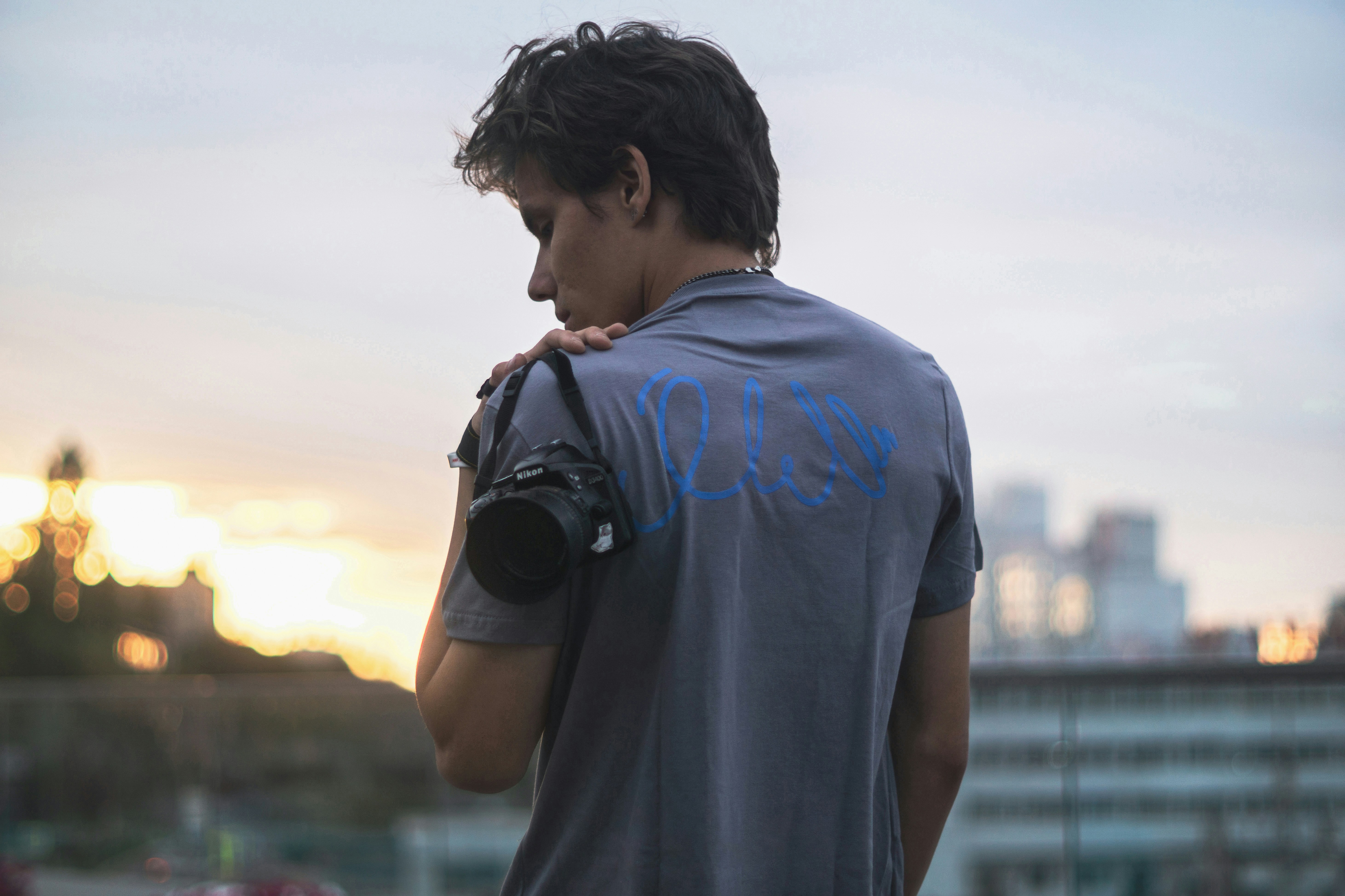 Photographer scouting a golden-hour rooftop location with a camera slung over his shoulder