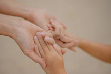 Adult and child hands gently holding each other.