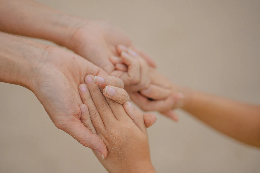 An adult and child gently holding hands