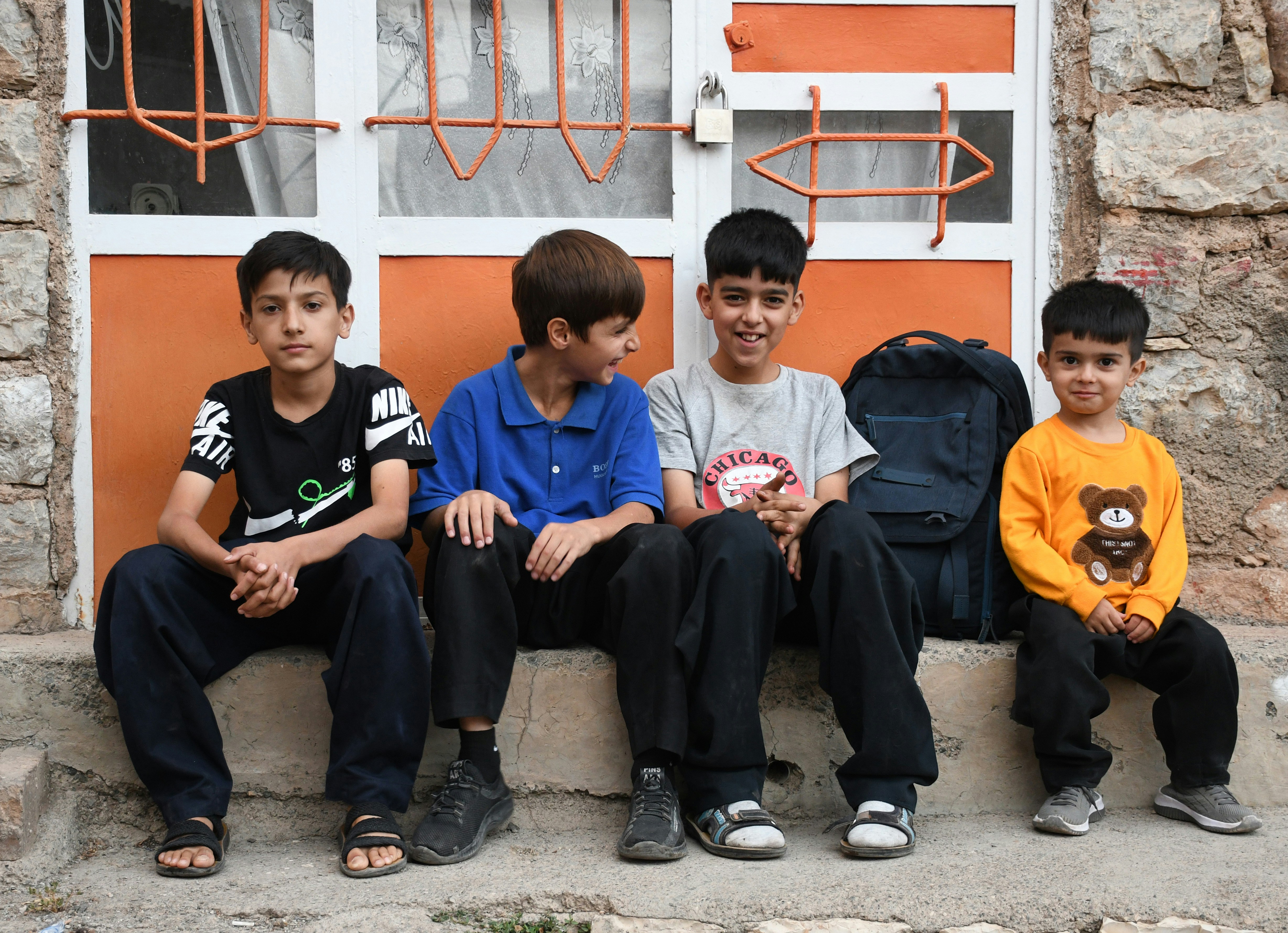 Four young boys sitting on steps outside a building.