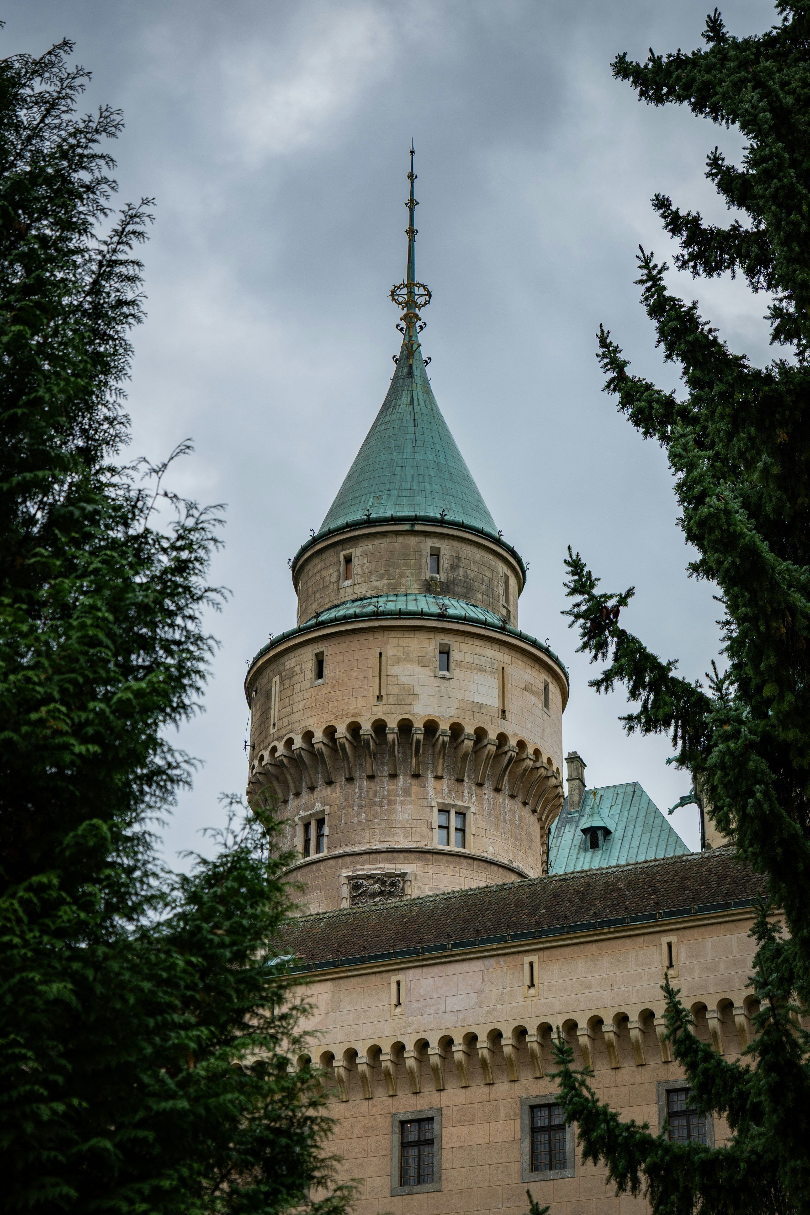 Torre del castillo con techo verde enmarcada por árboles