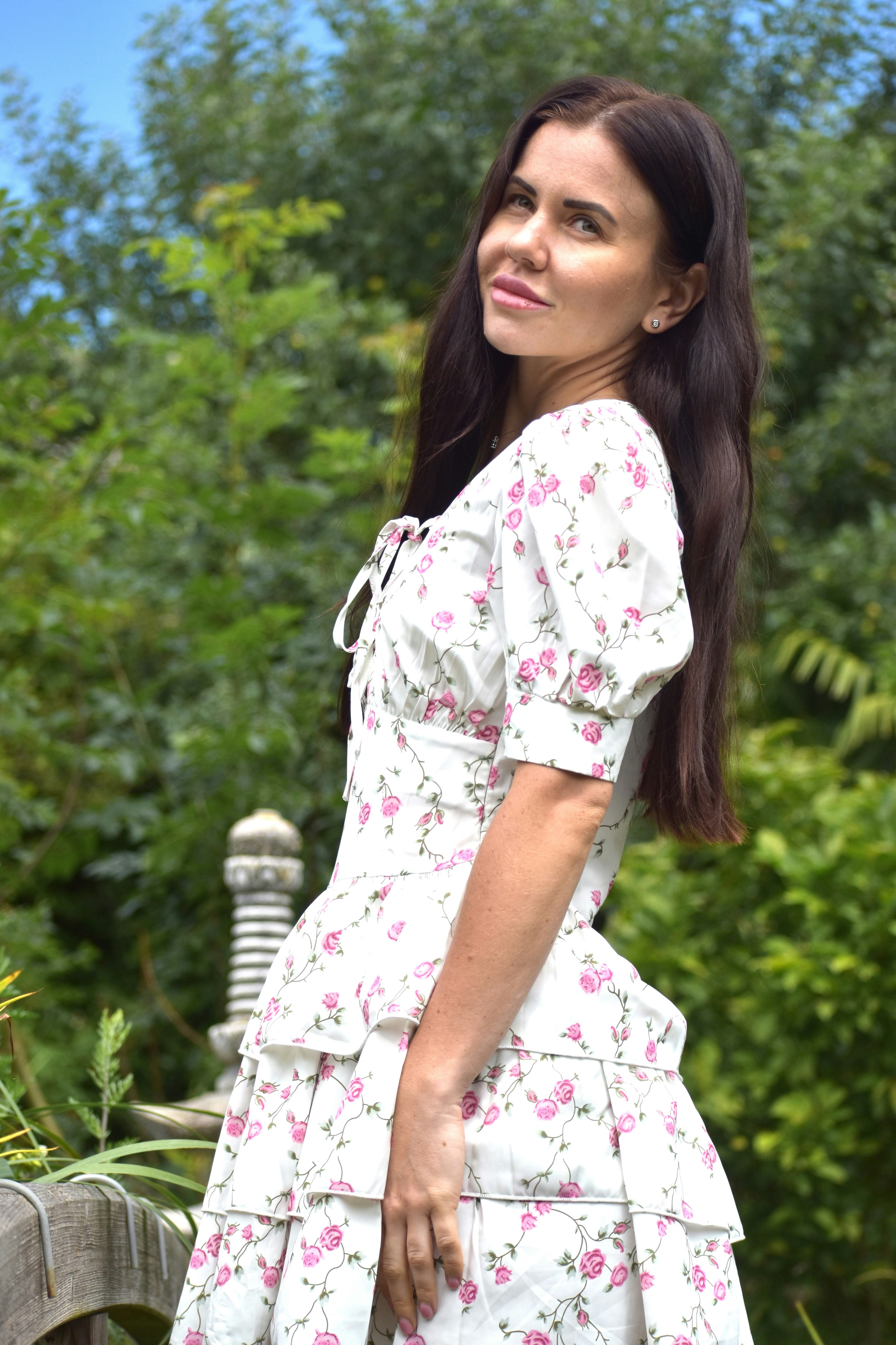 Una donna in abito floreale sta all'aperto.