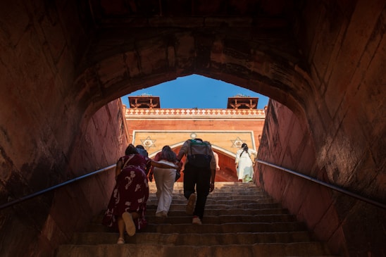 People ascend stairs towards ancient architecture