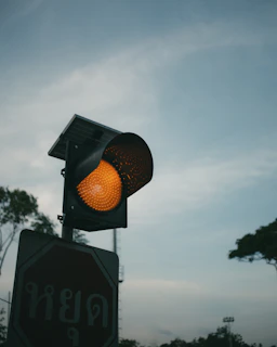 Traffic light shows yellow against a cloudy sky