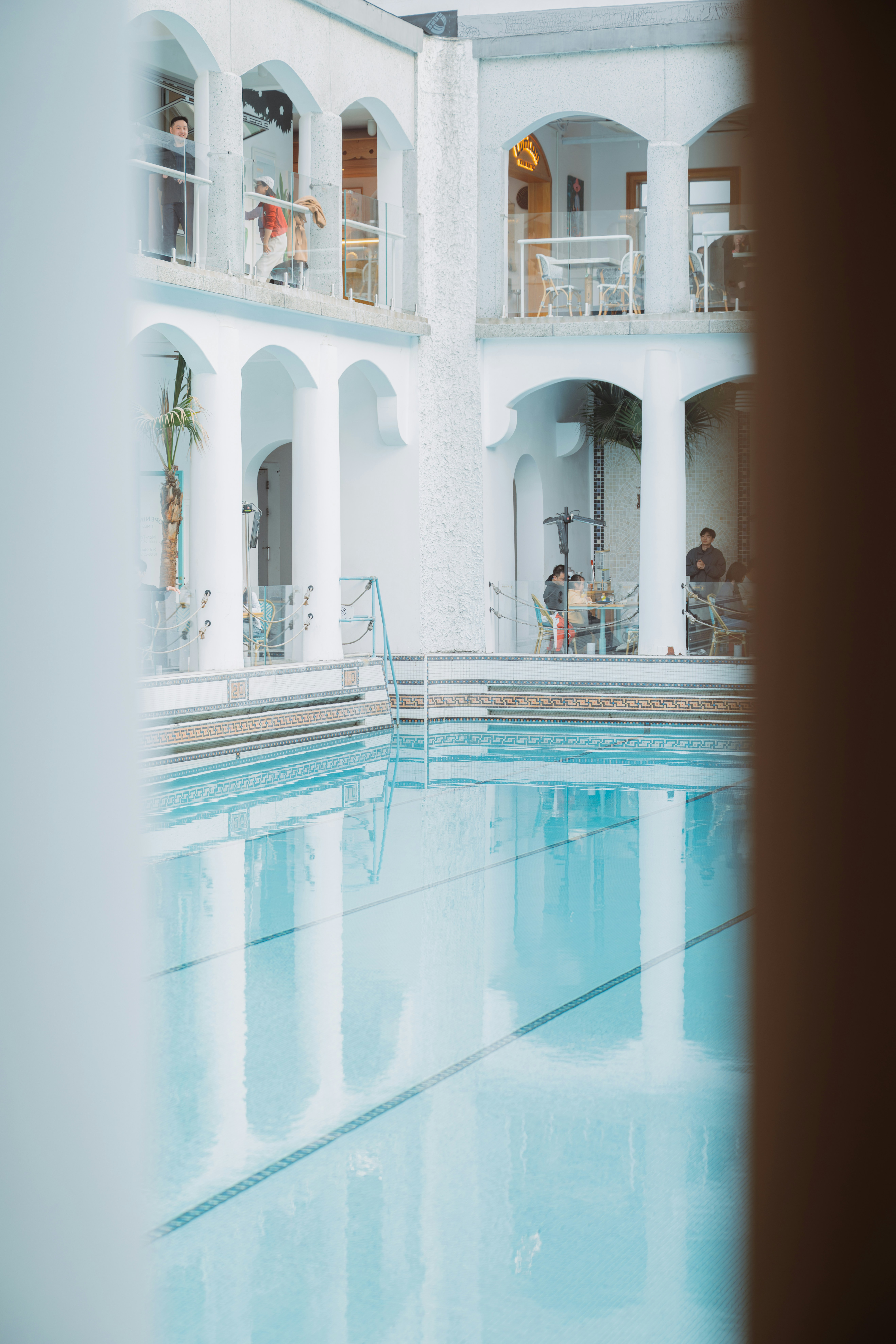 Piscine intérieure avec des gens sur les balcons au-dessus.