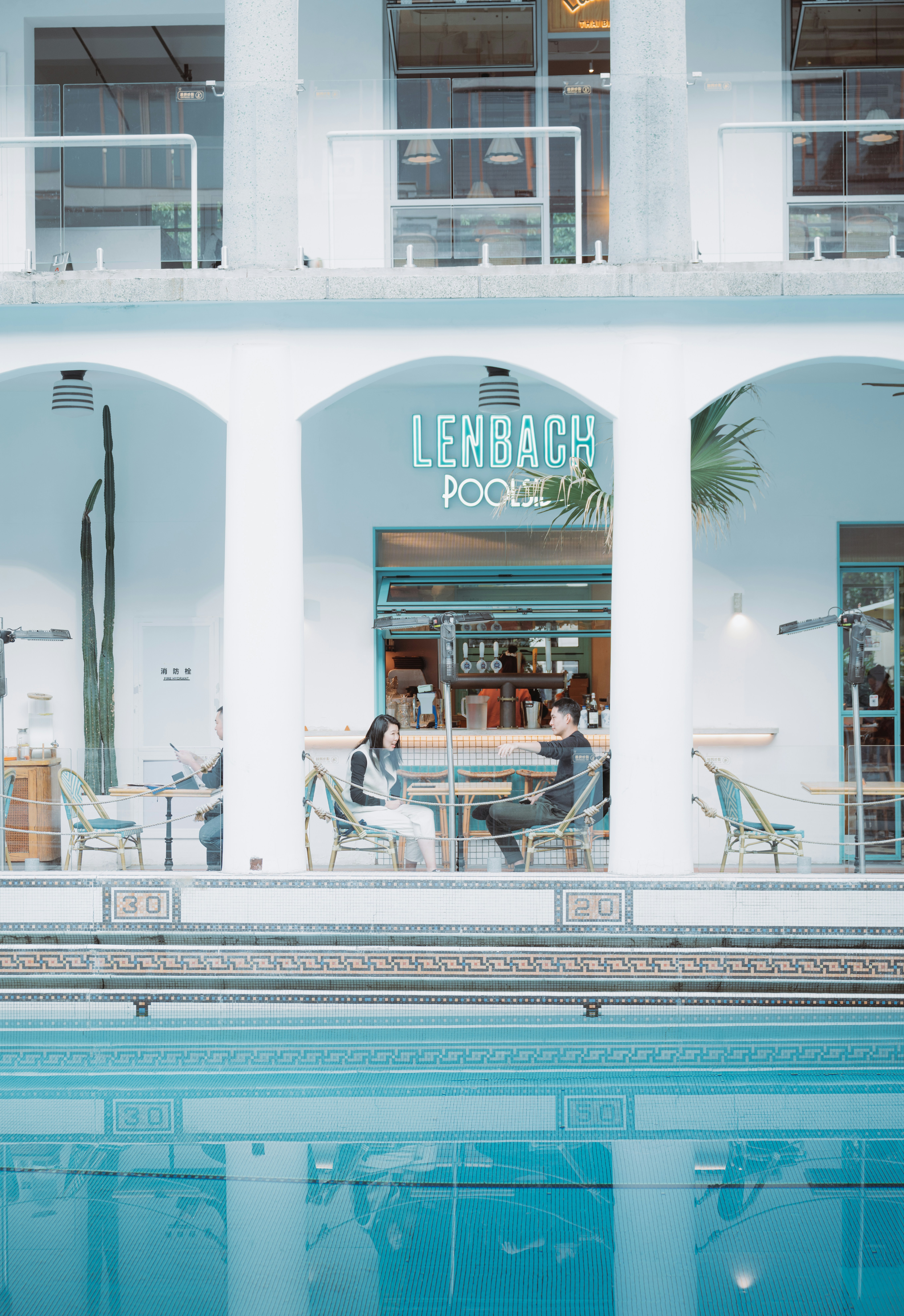 Deux personnes assises à des tables au bord d’une piscine