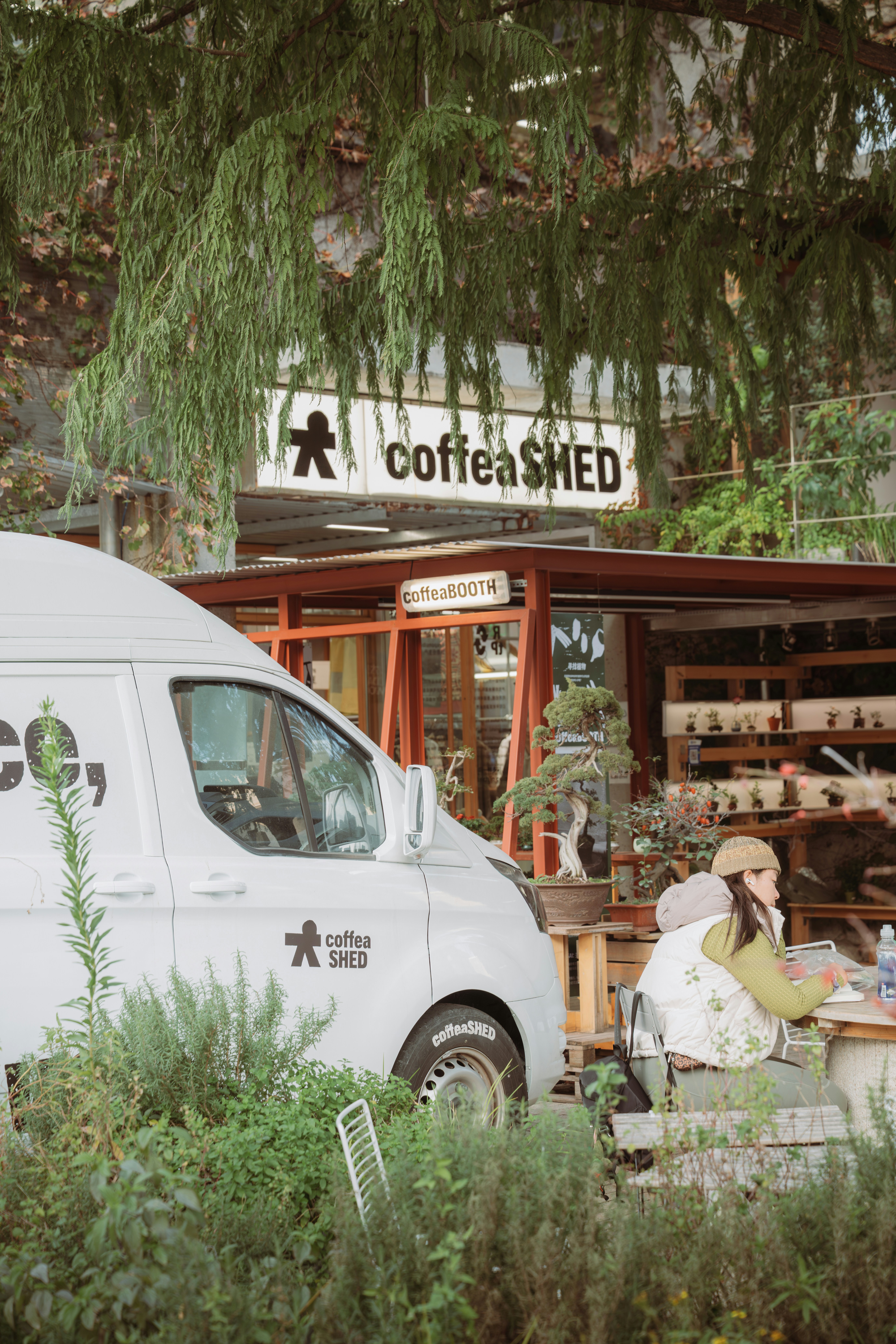 Un van blanc garé devant un café appelé coffee shed.