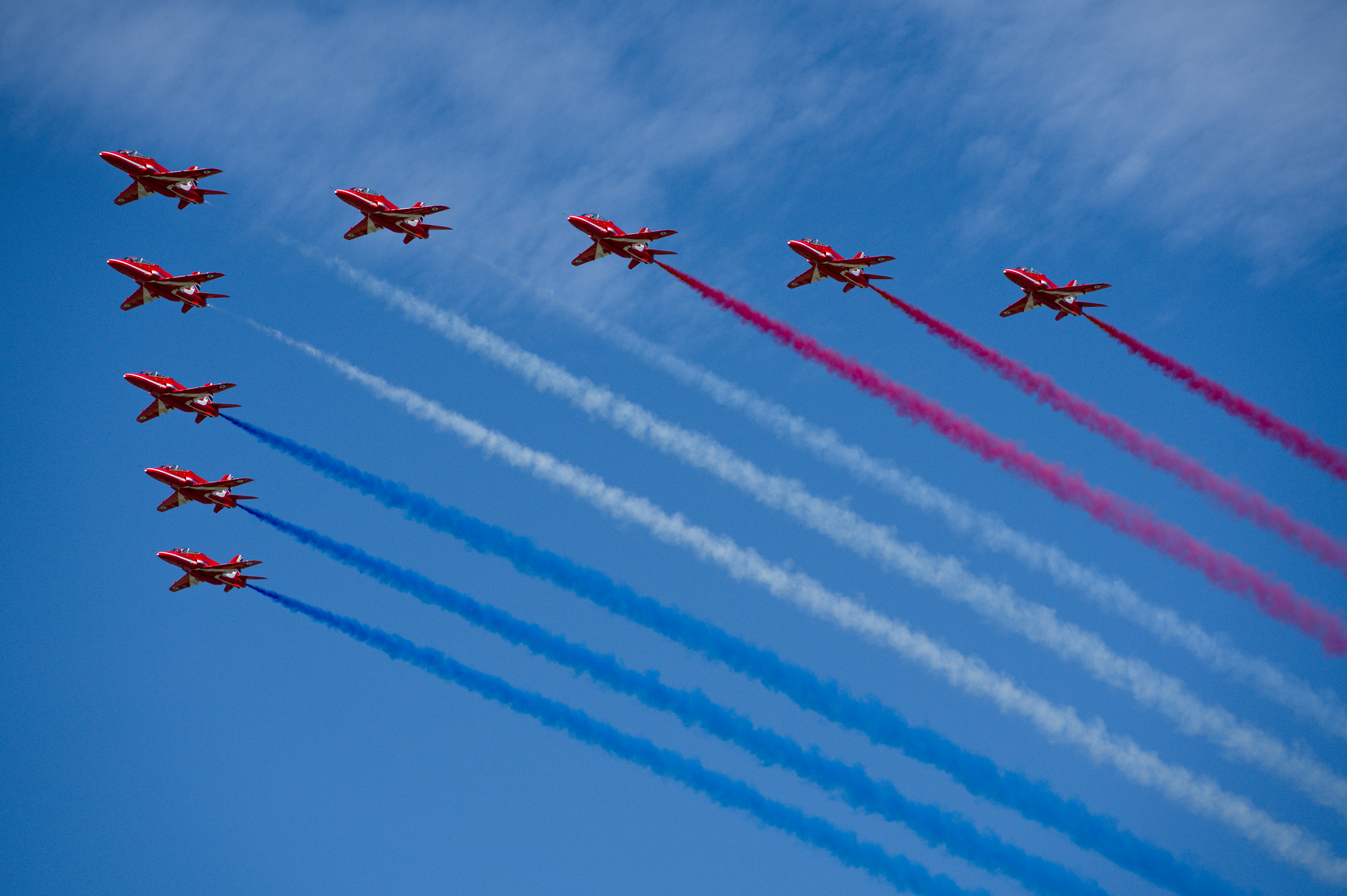 Red arrows fly in formation leaving colored smoke trails.