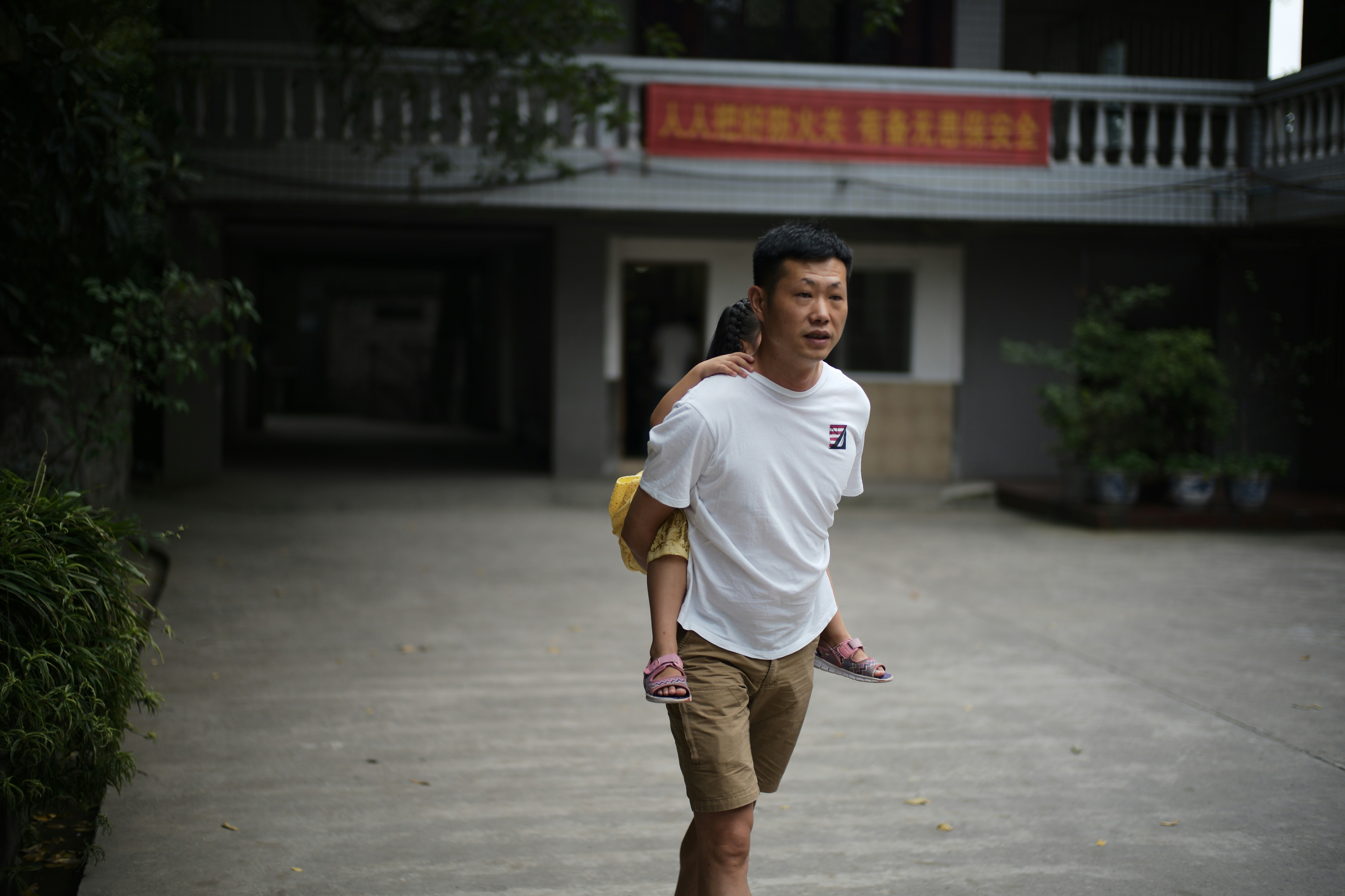 Man carrying a child on his back outdoors.