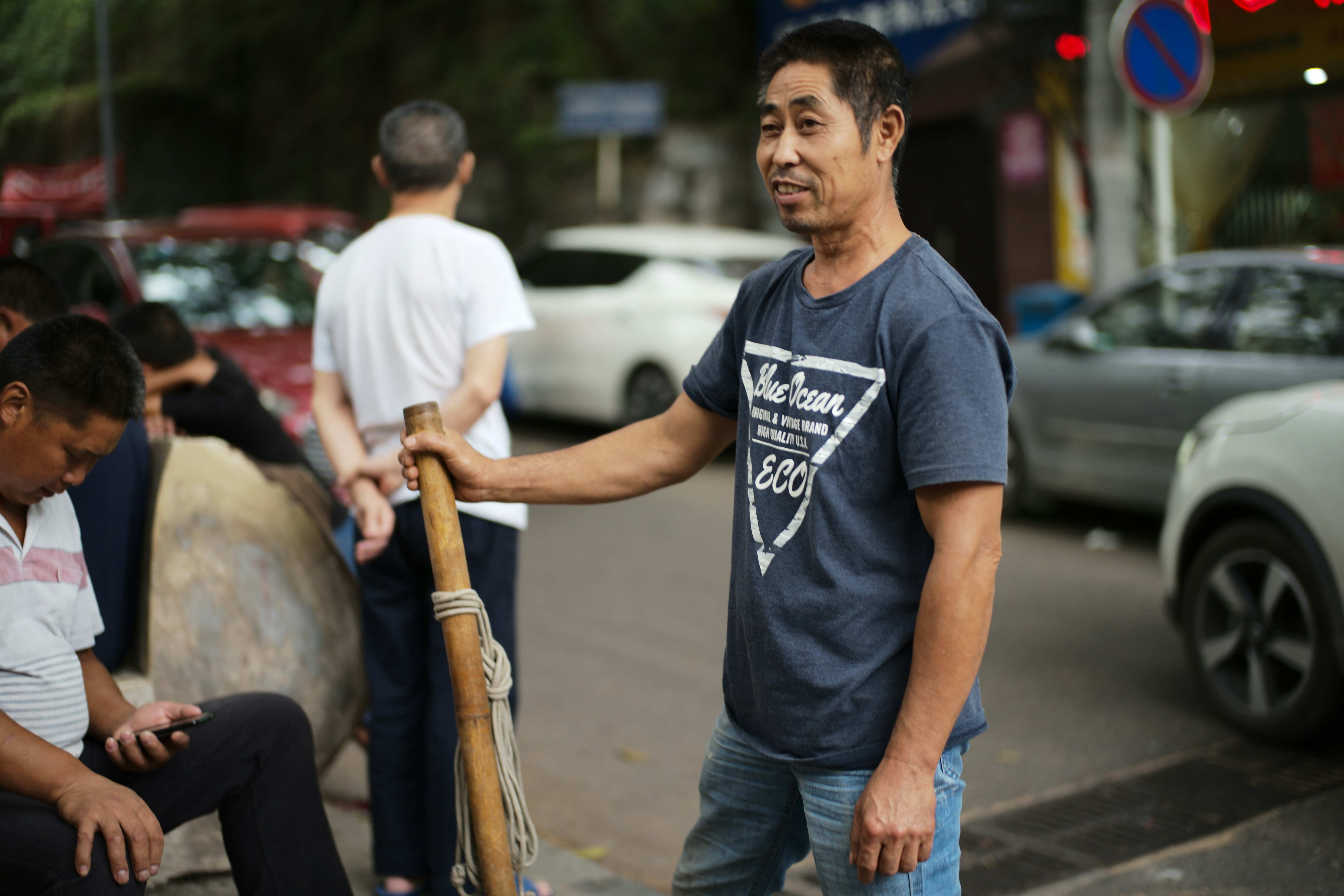 Man with a stick standing on a street.