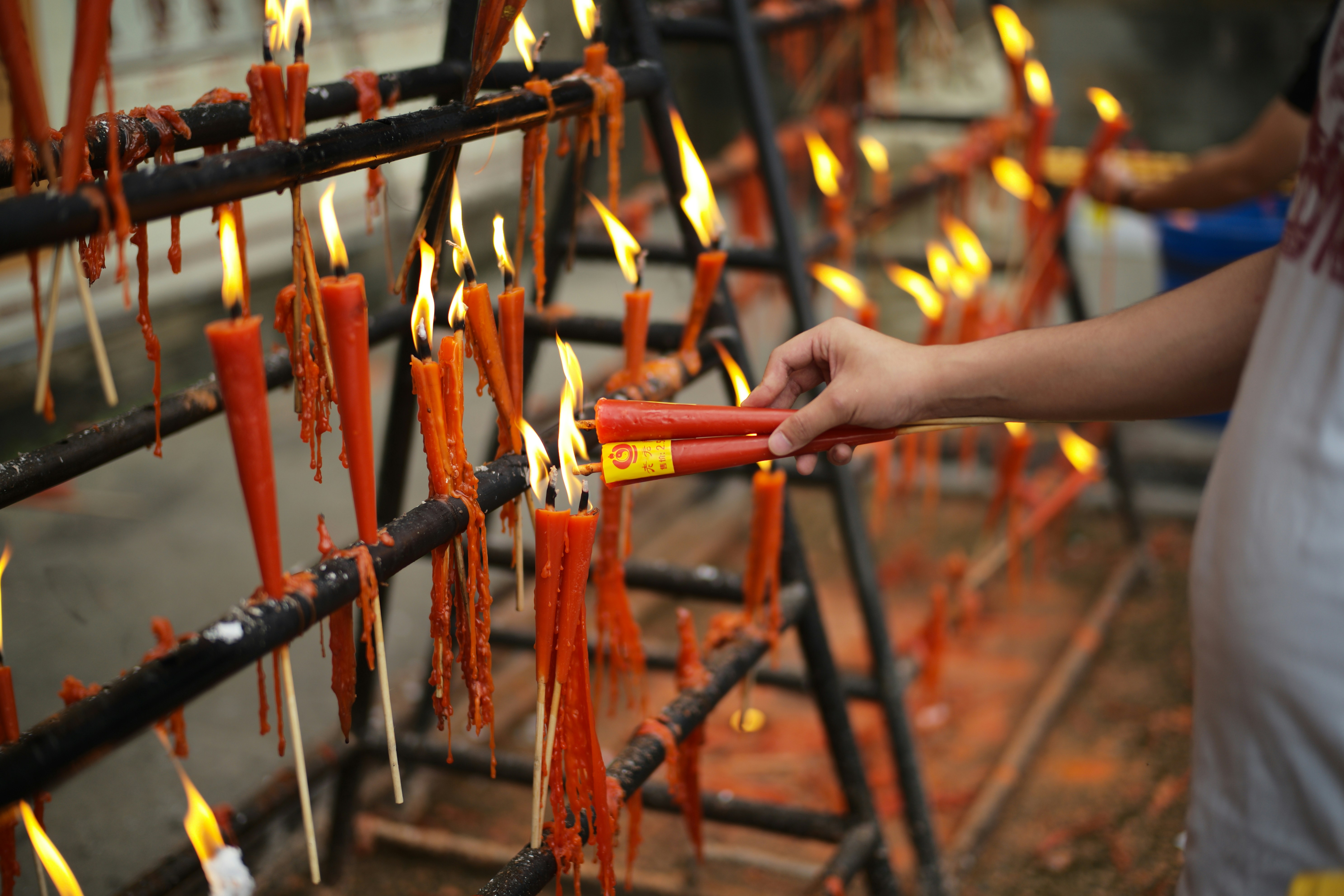 Hand lighting red candles on a rack