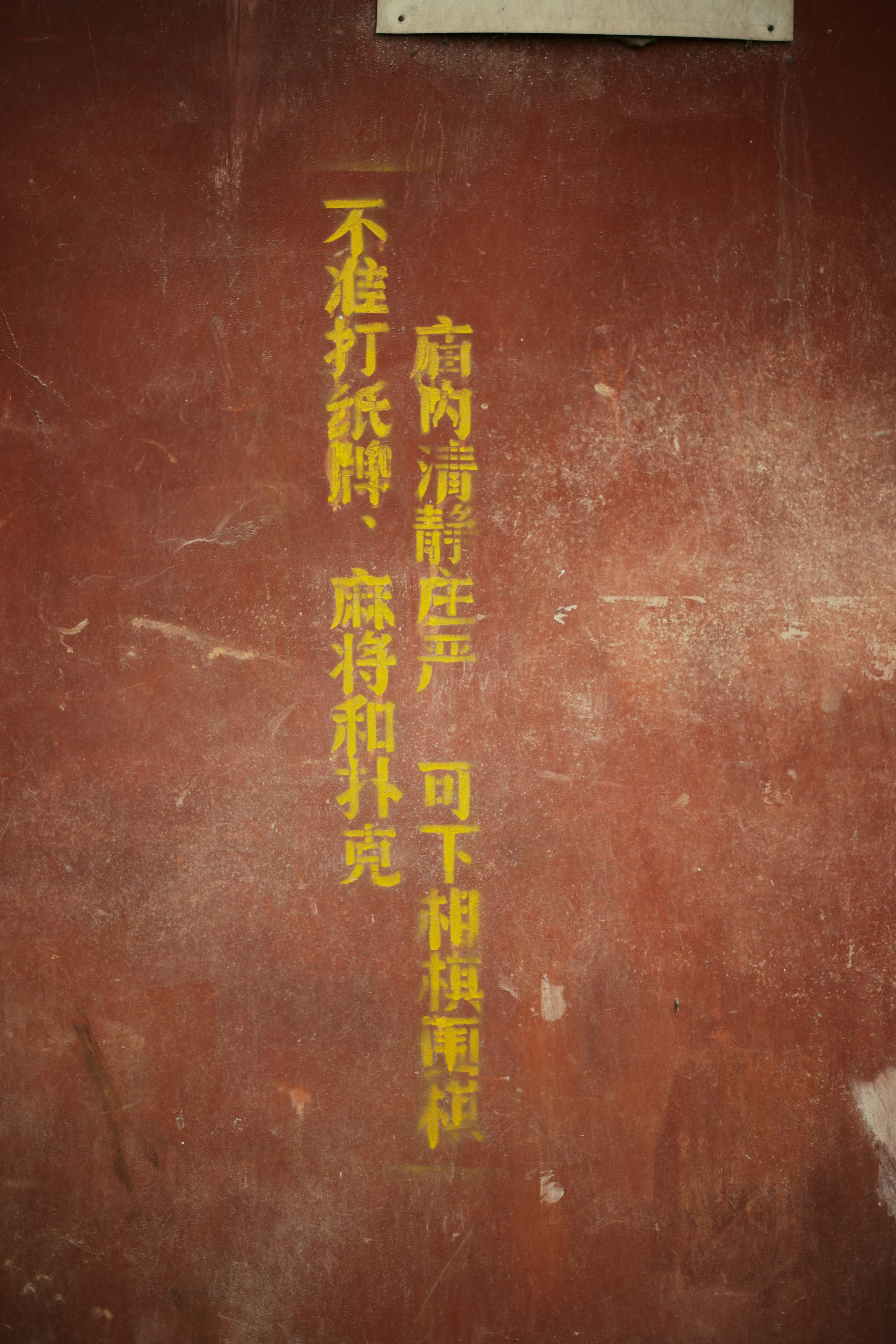 Yellow chinese text on a dusty red wall