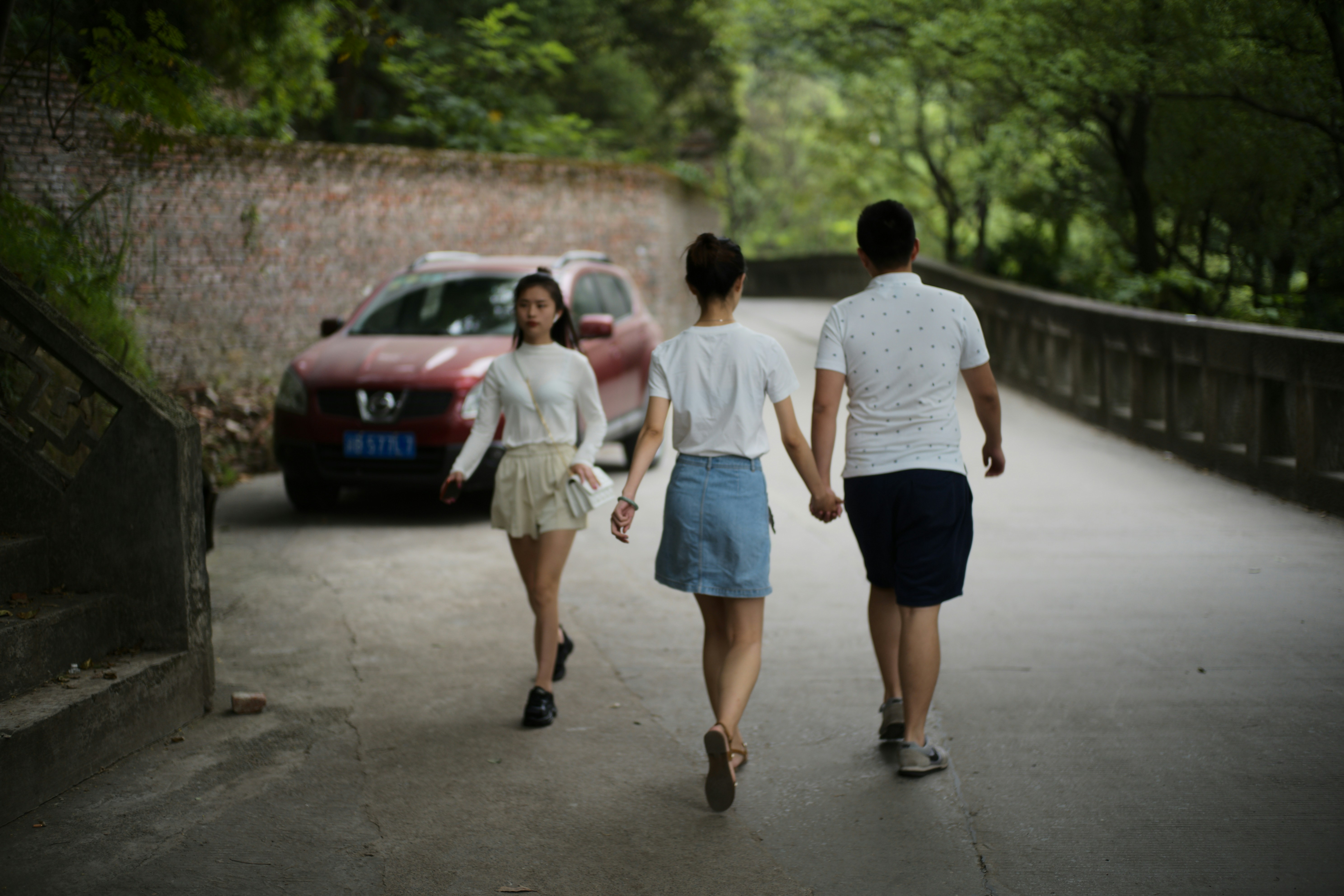 Tres personas caminando de la mano por un camino.