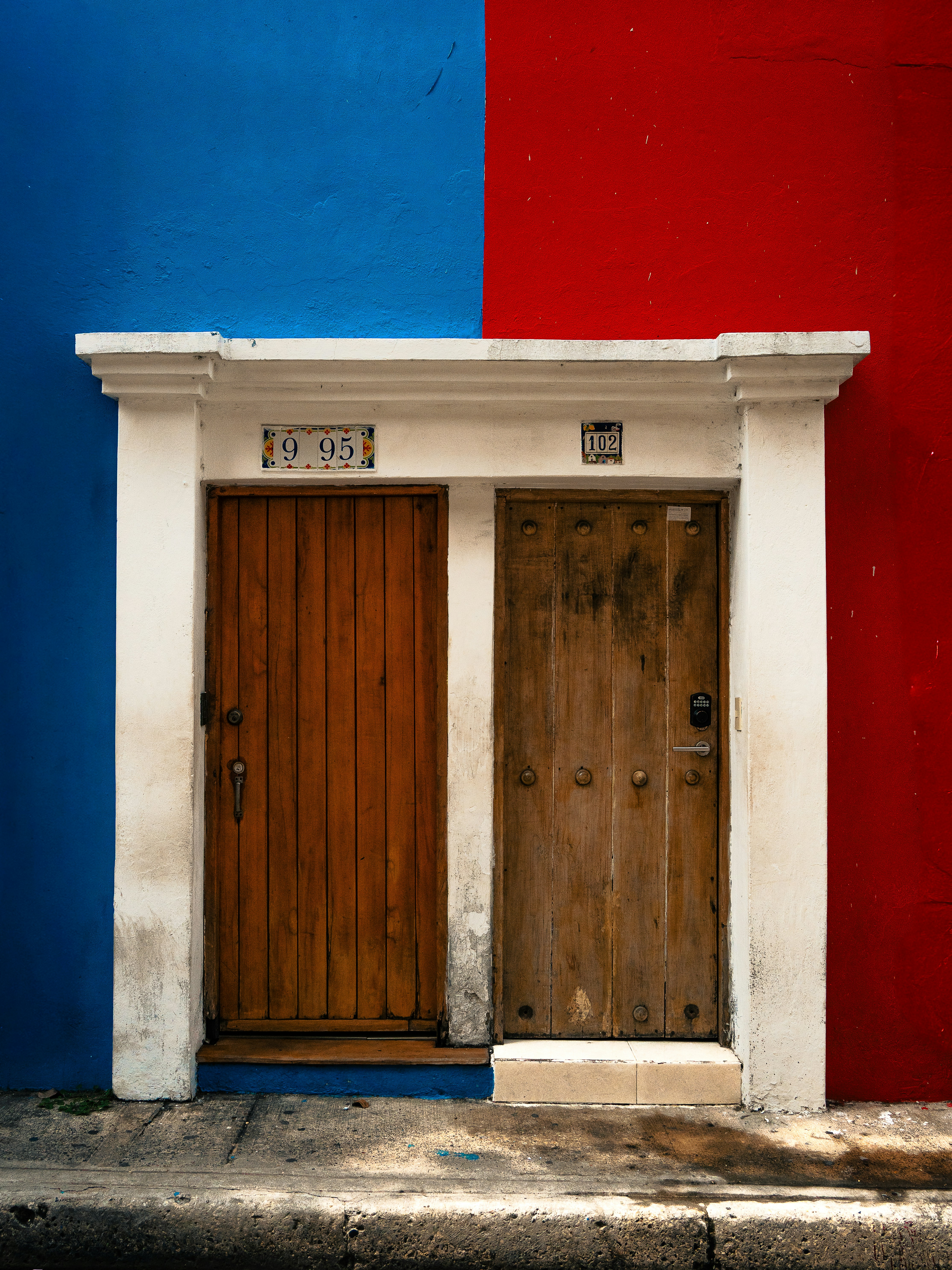 Two wooden doors against a split blue and red wall