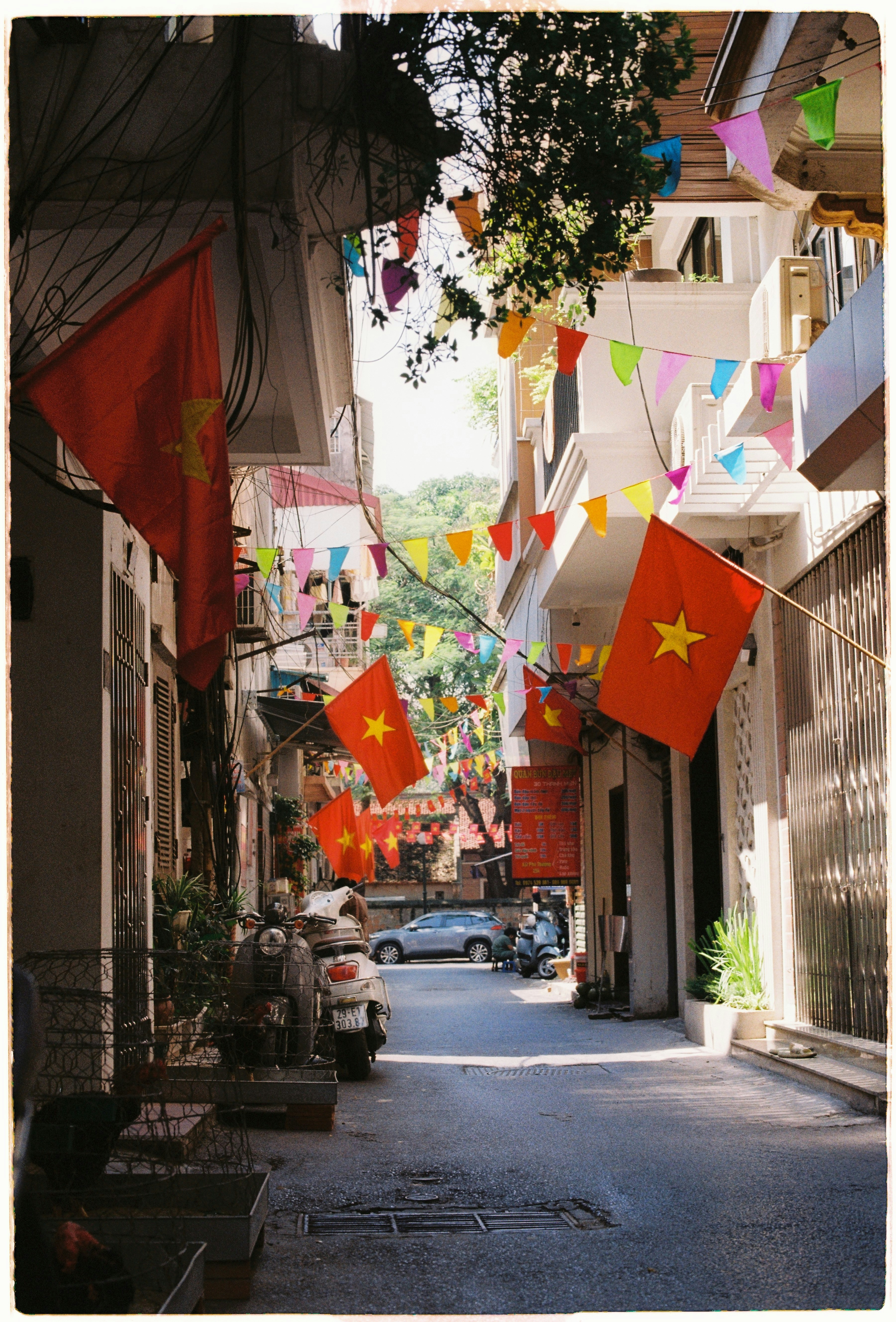 Vietnamese flags and colorful bunting decorate a narrow street.