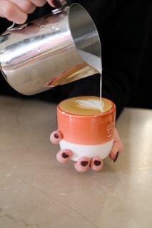 Barista pouring steamed milk into coffee for latte art.