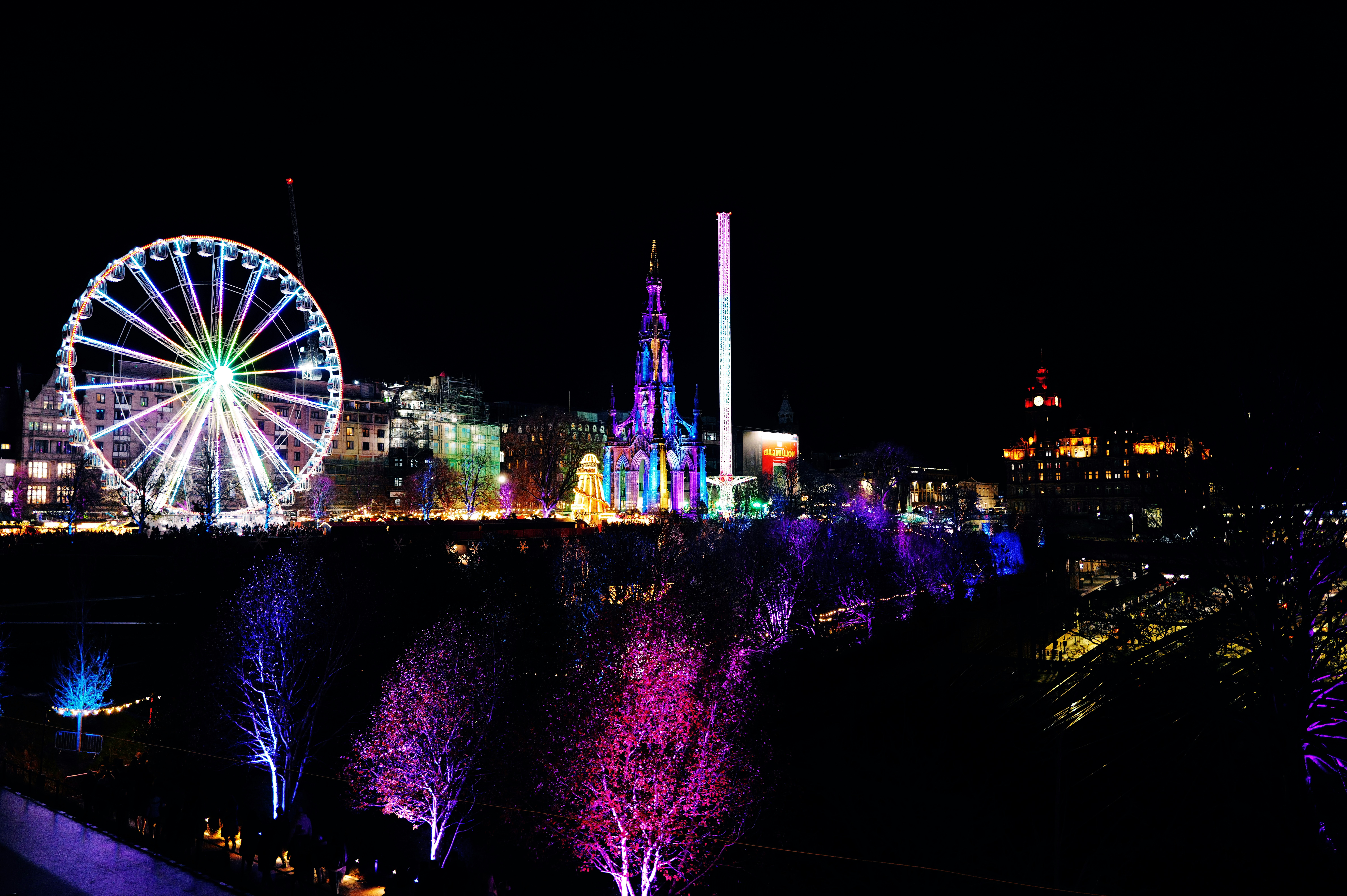 City skyline with ferris wheel and colorful lights at night