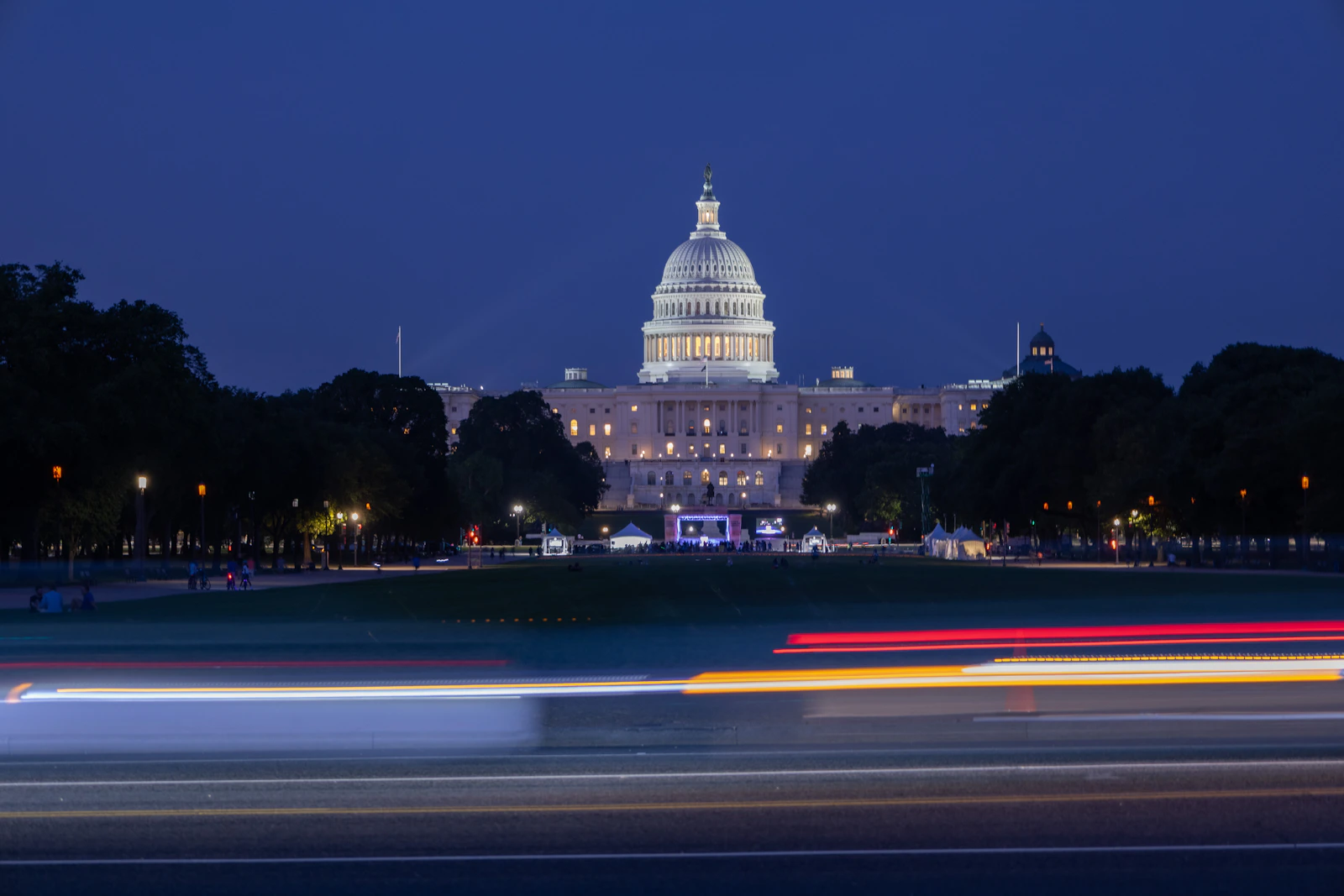 United States Capitol building at night with red and white car light trails streaking past