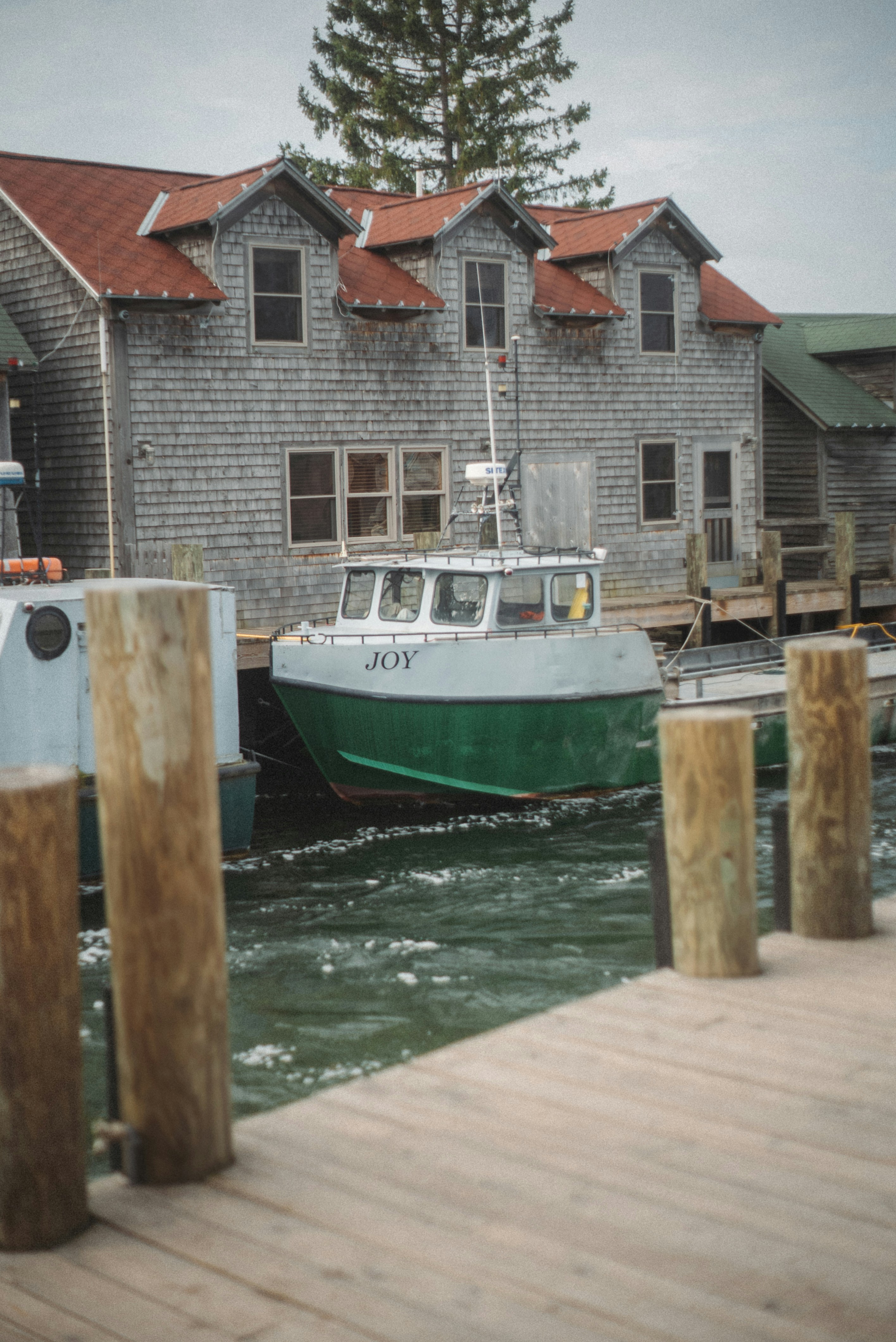 A green and white boat named joy at dock.