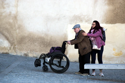 Young woman helps elderly man in wheelchair