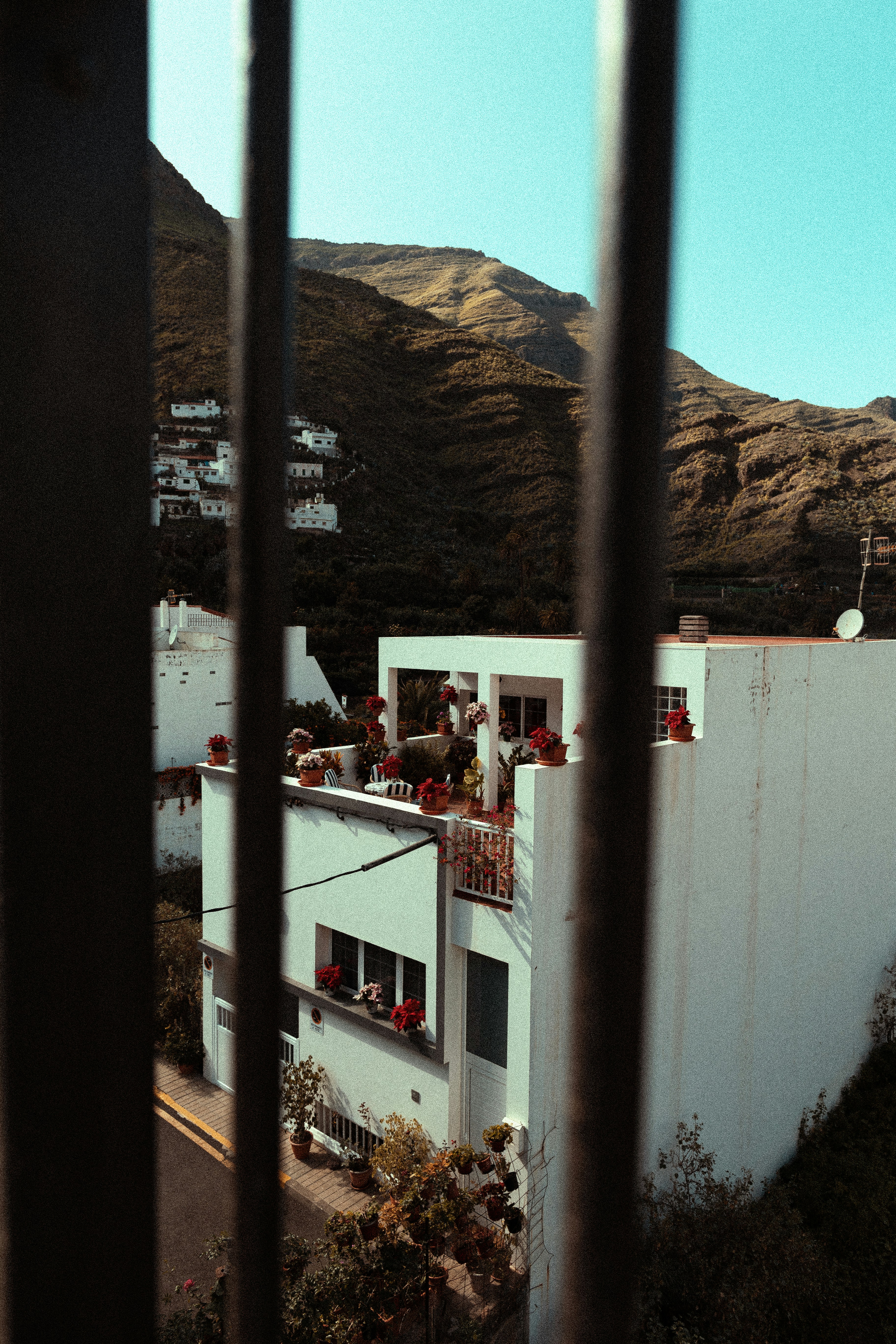 White buildings nestled on a hillside under mountains.