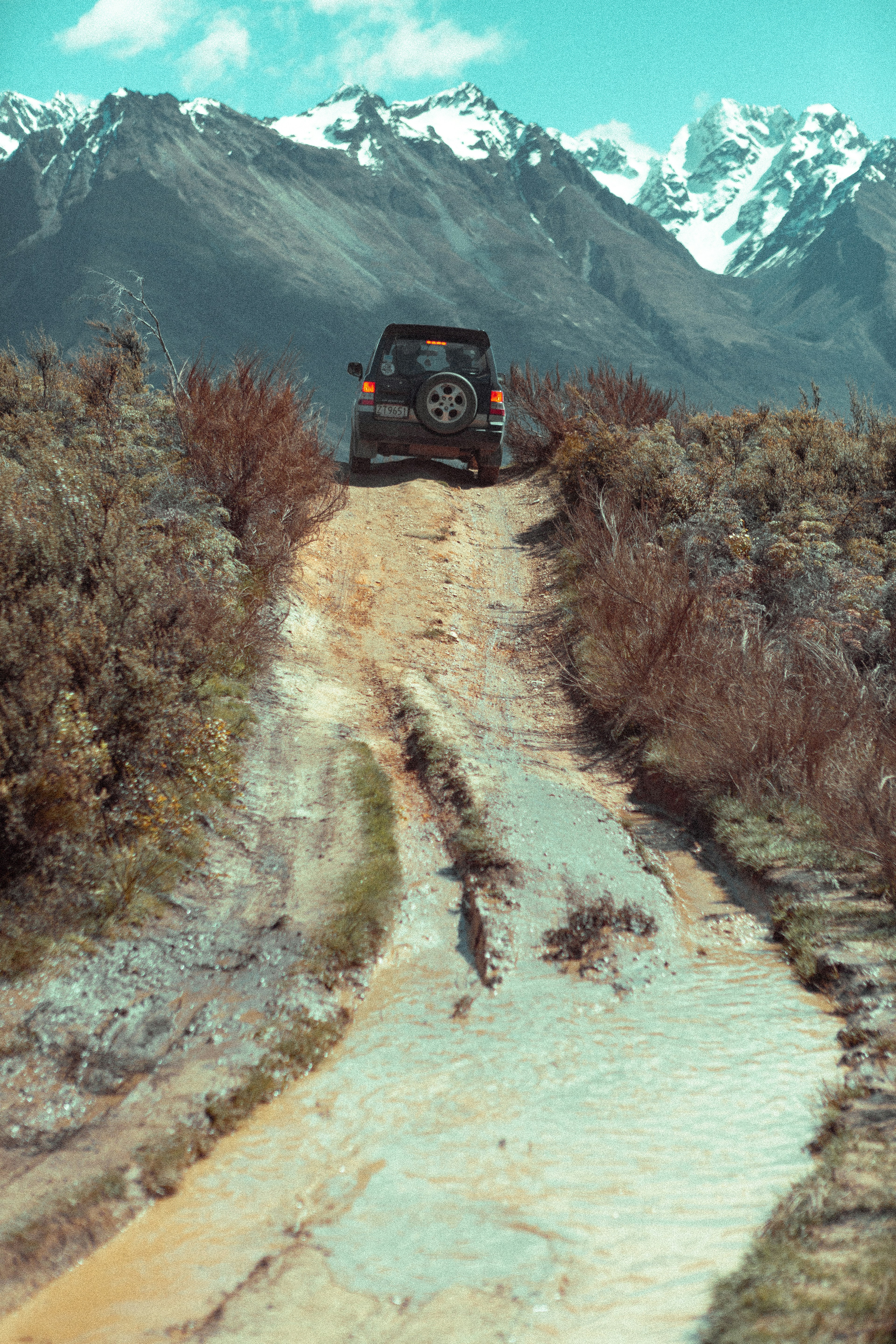 Off-road vehicle driving up a muddy mountain path.
