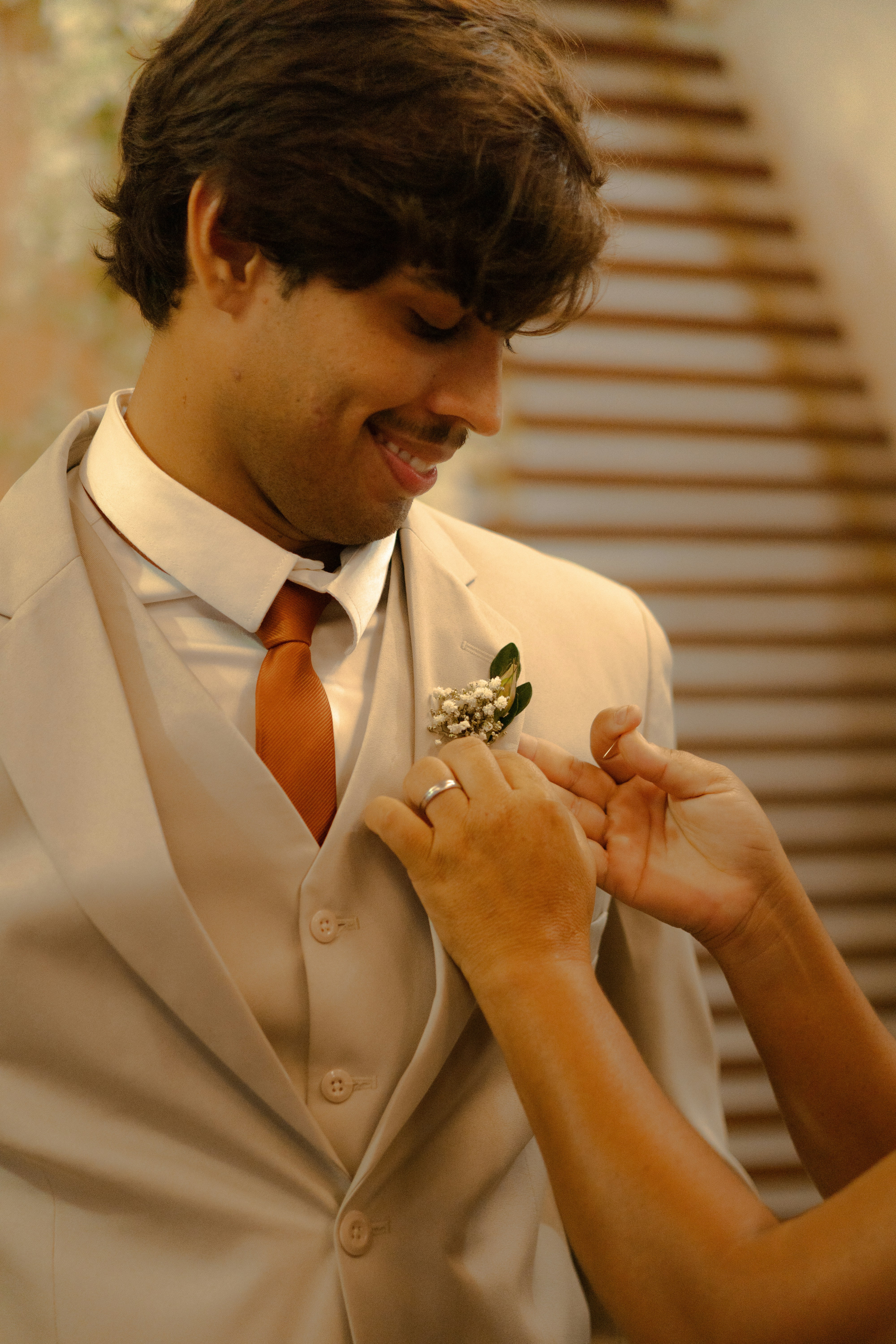 Groom smiling as boutonniere is adjusted