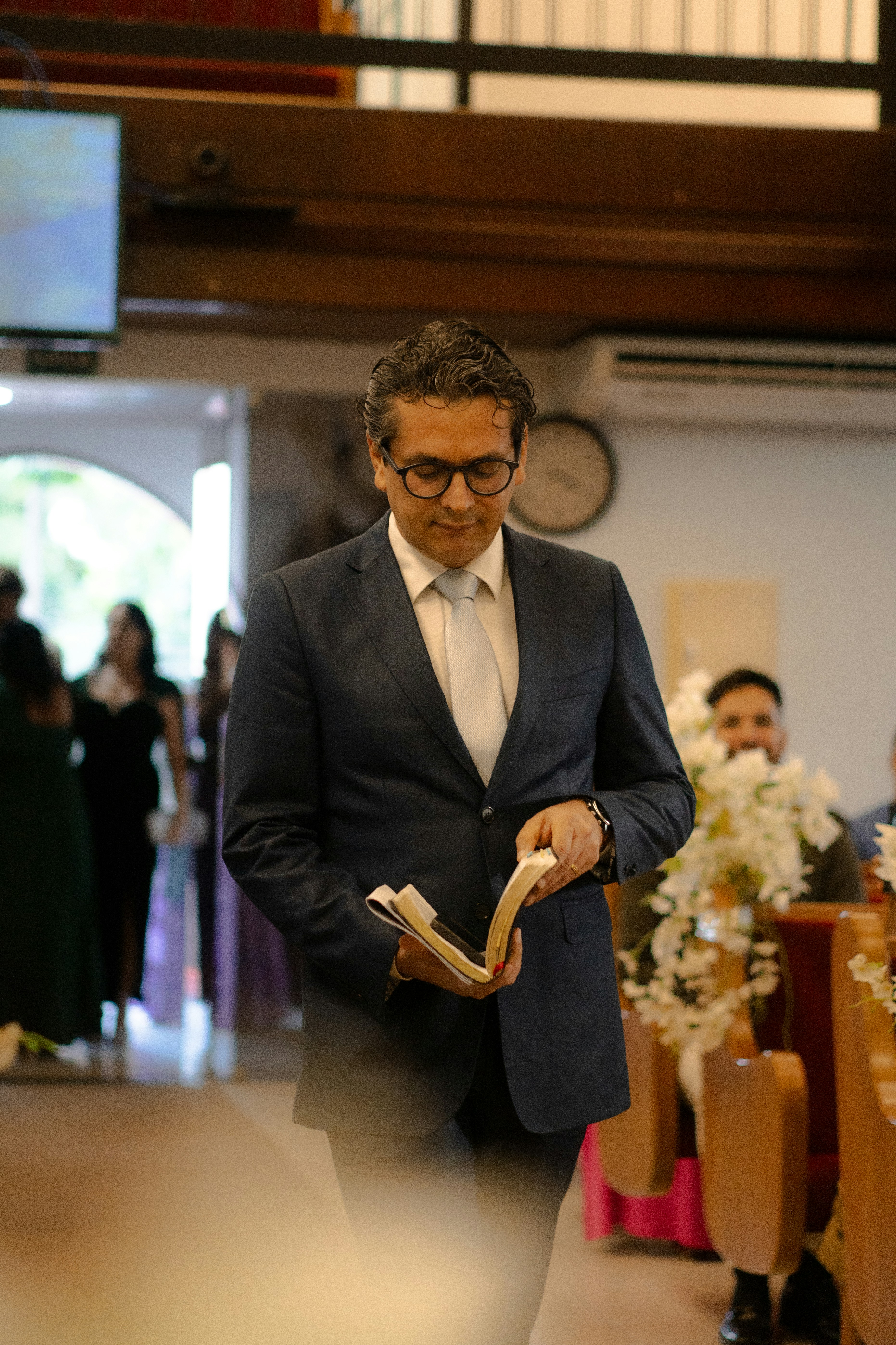 Man in suit holding a book in a church.