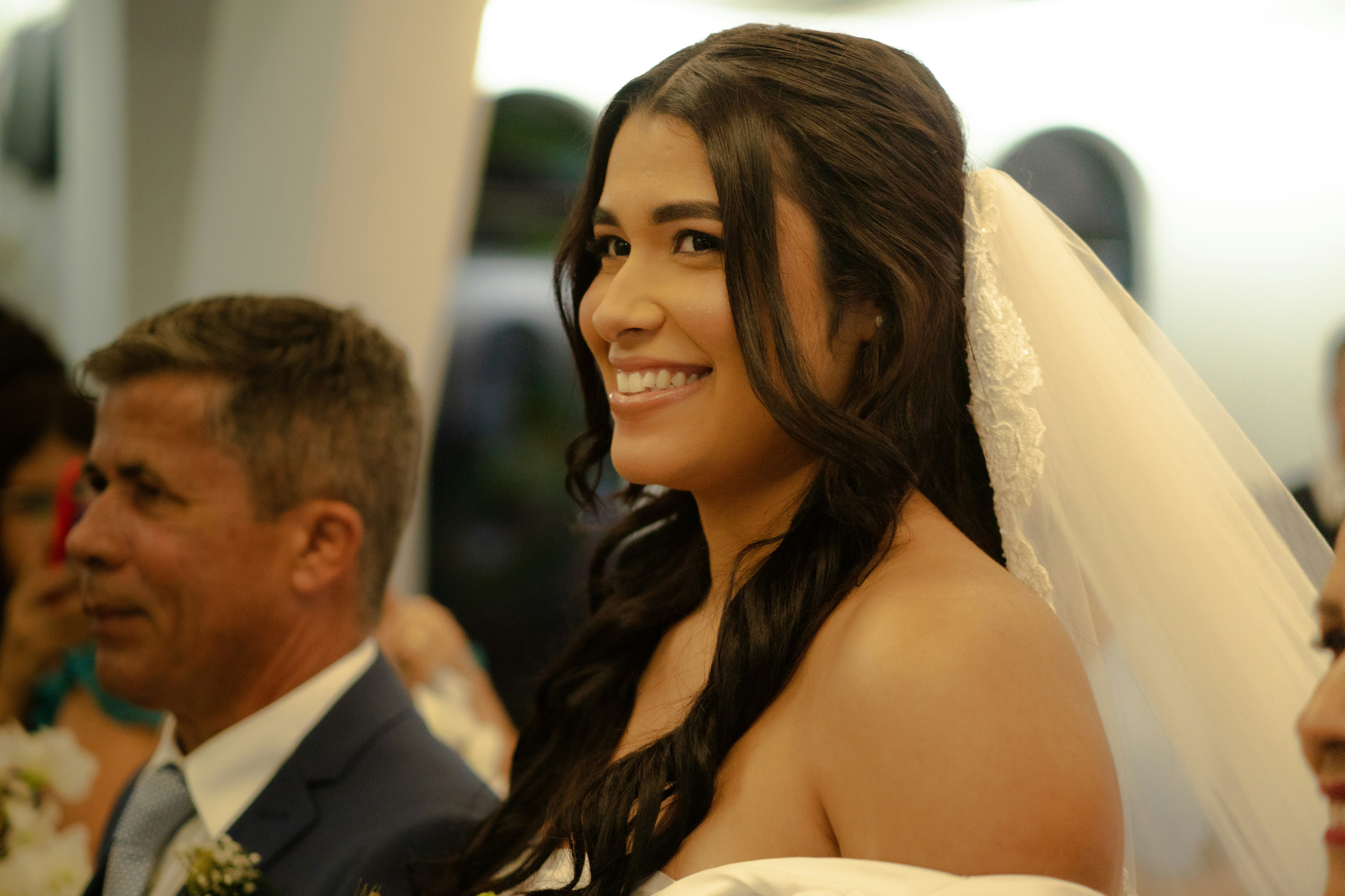 A smiling bride in a white dress with a veil.