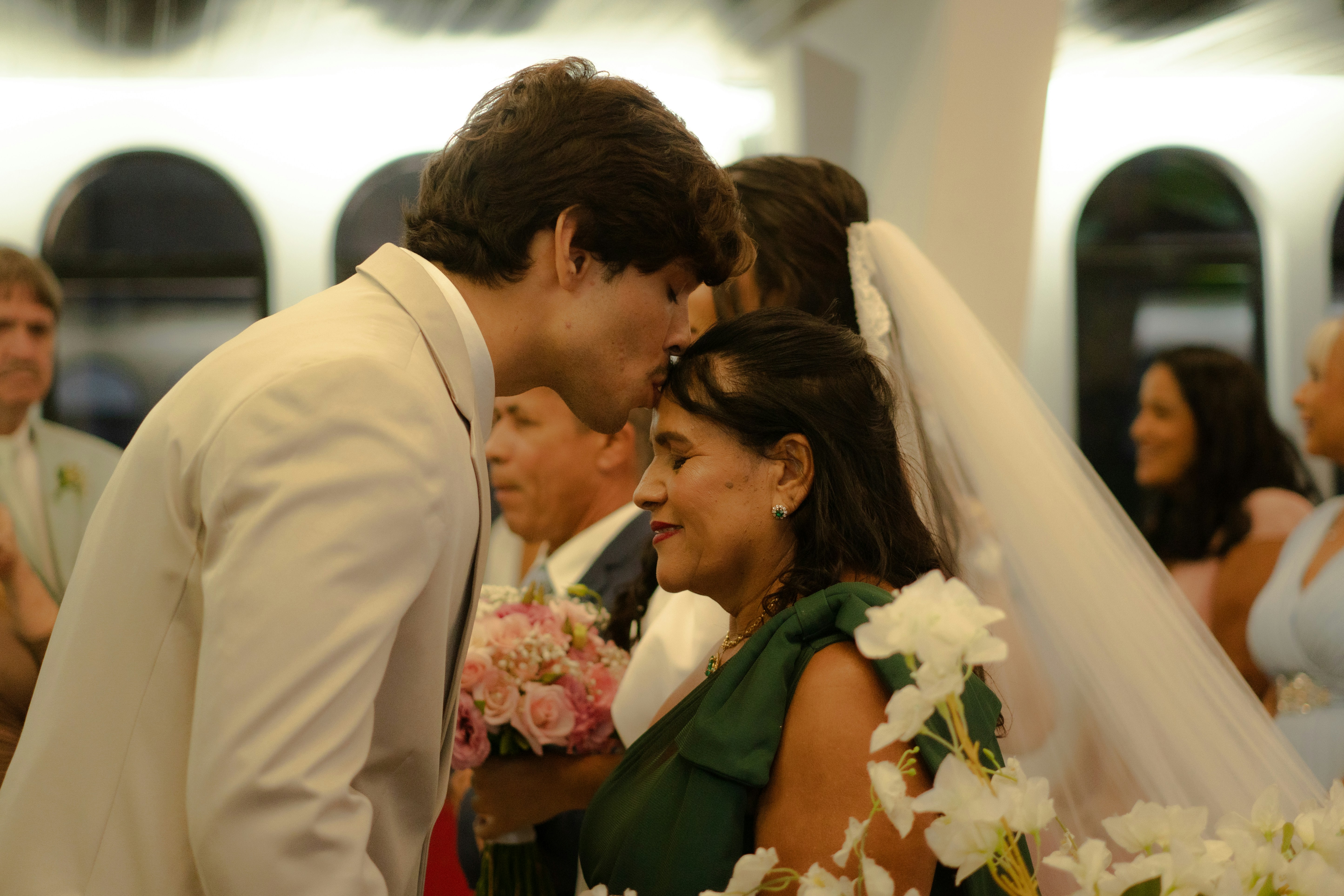 Groom kisses mother's forehead at wedding ceremony