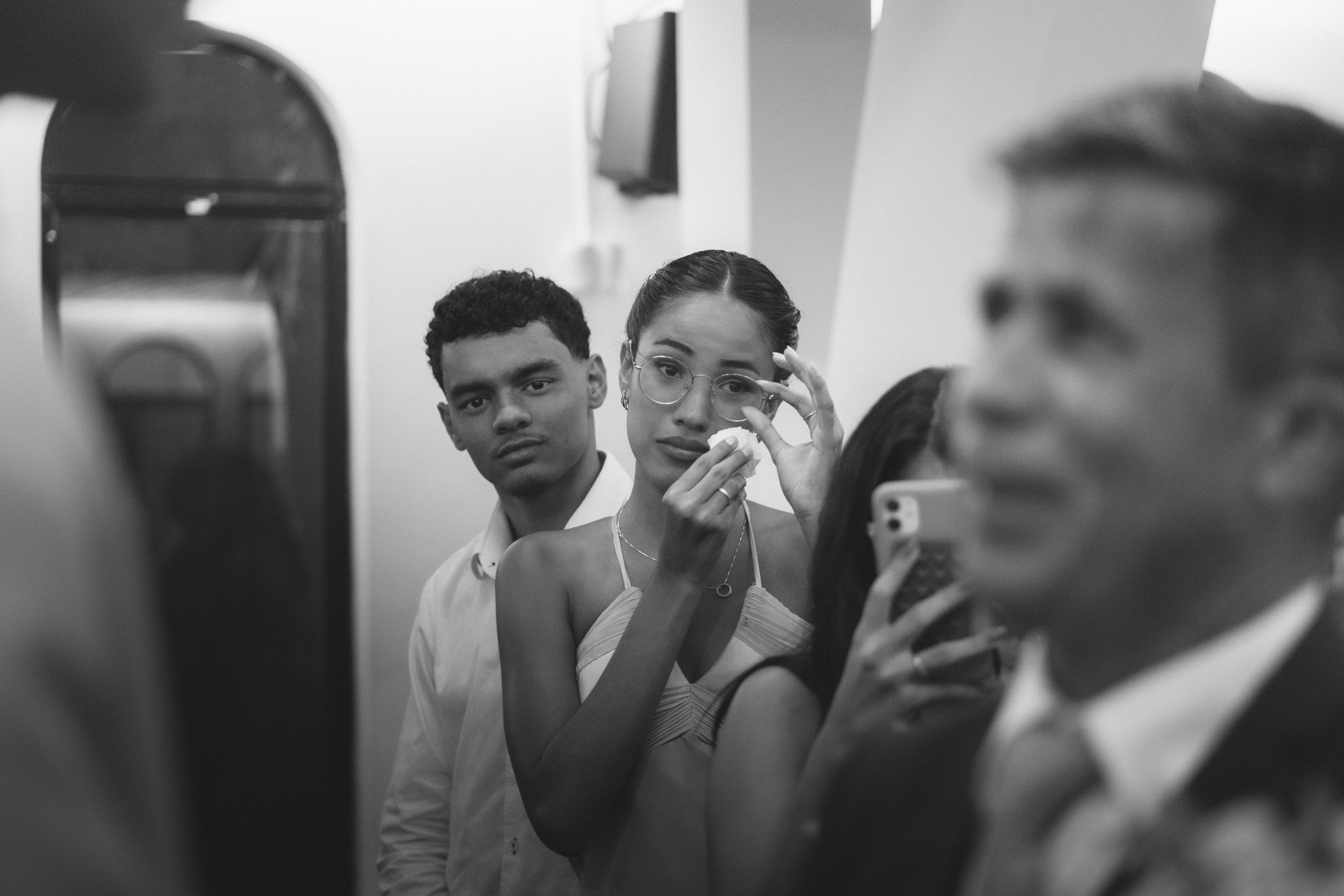 Woman dabbing tears with tissue, man watches.