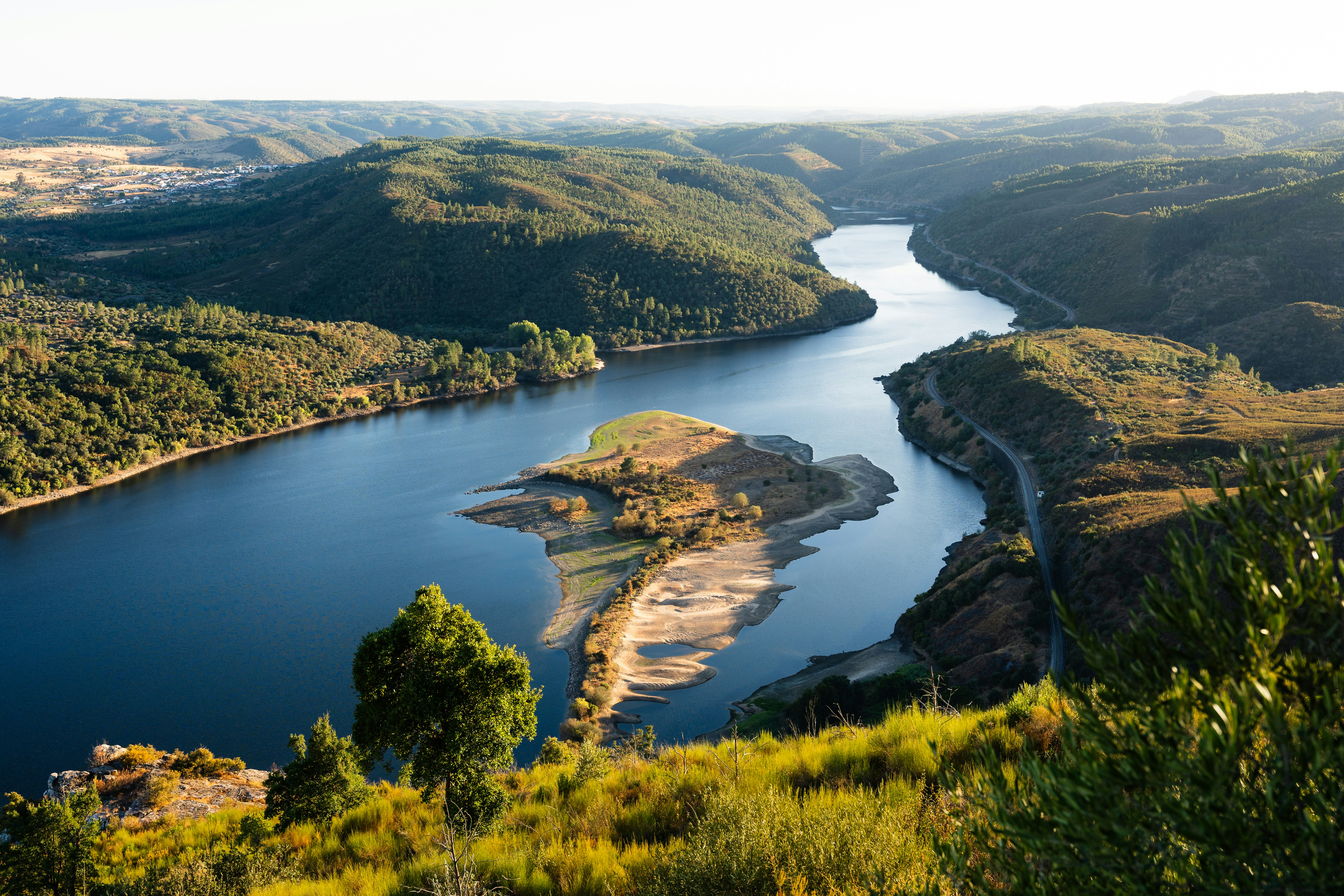Ein gewundenen Fluss fließt durch ein üppig grünes Tal.