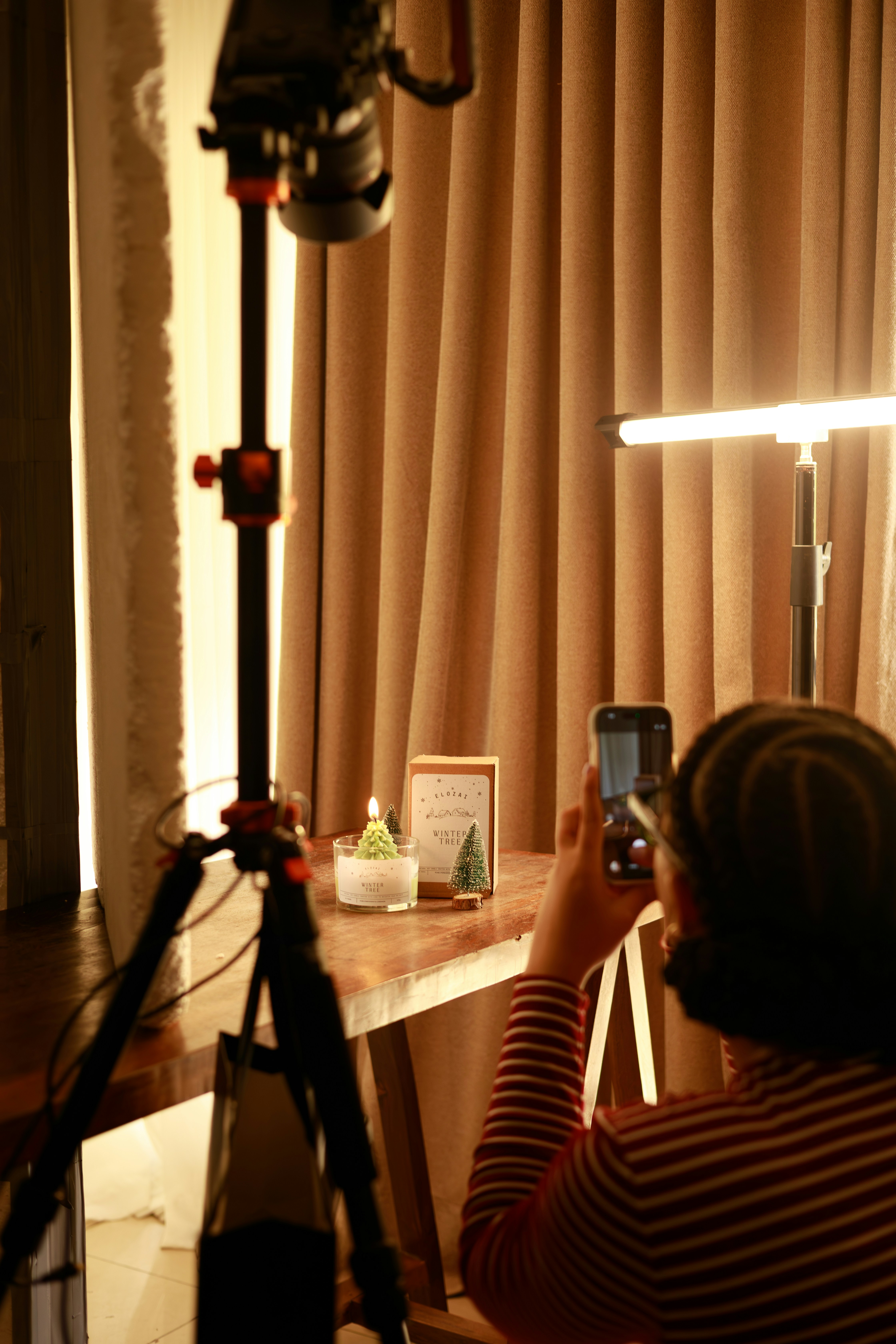 Person photographs a small candle on a table.