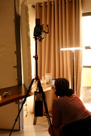 Person filming with camera on tripod indoors