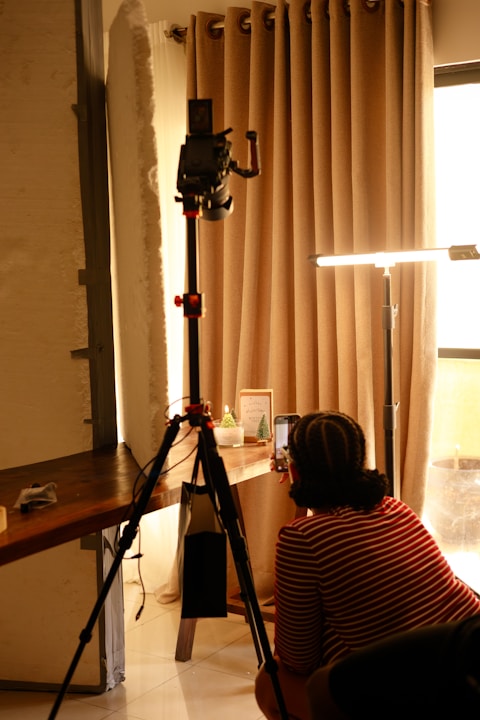 Person filming with camera on tripod indoors