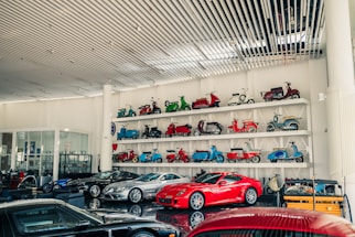 Collection of vintage scooters and modern cars displayed.